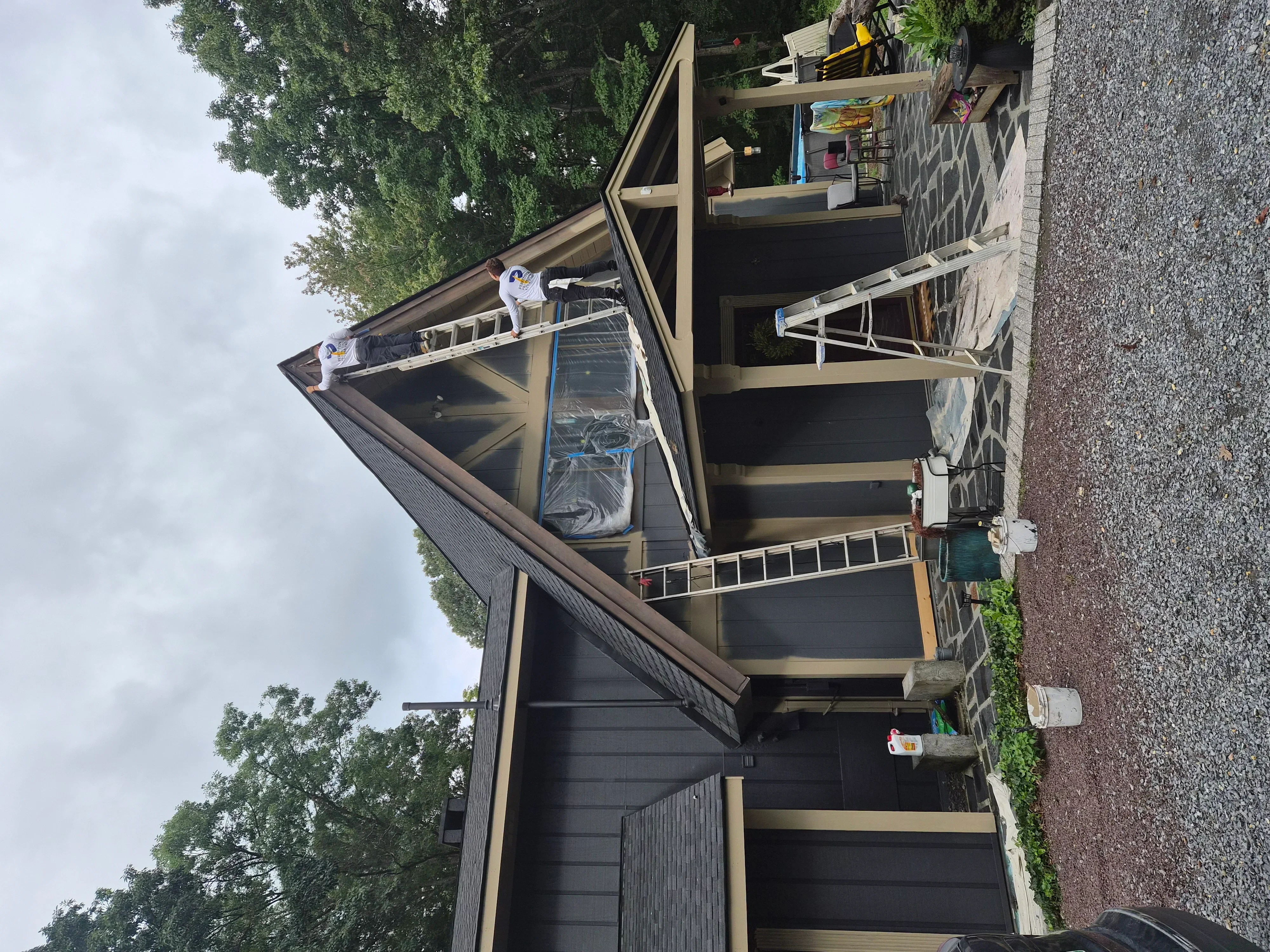 Dark charcoal exterior siding with tan trim, painted fascia, soffit, and detailed woodwork
