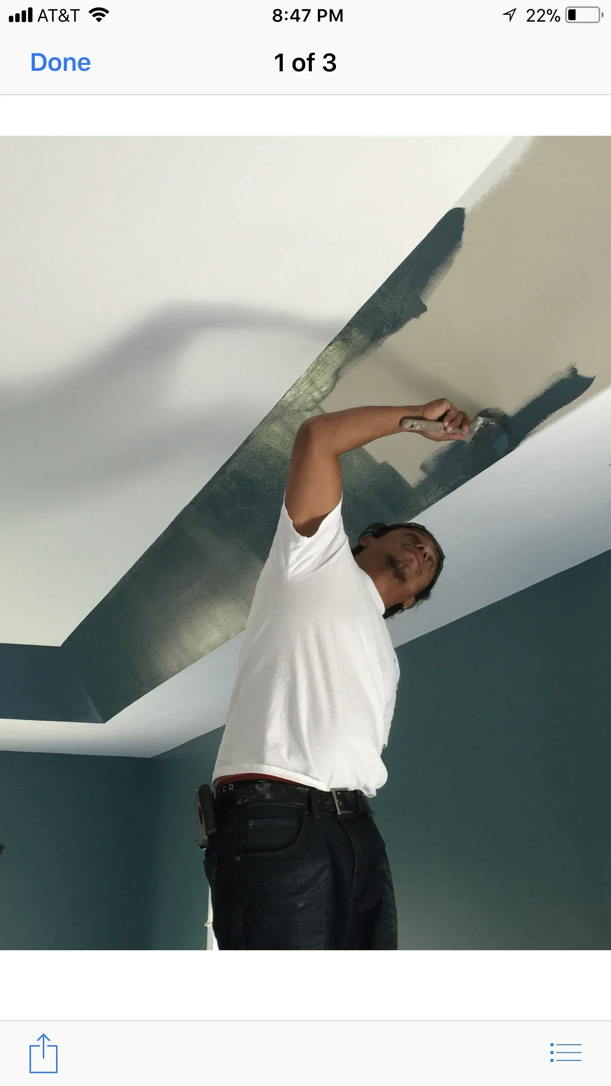 Worker applying joint compound to drywall ceiling seams with putty knife