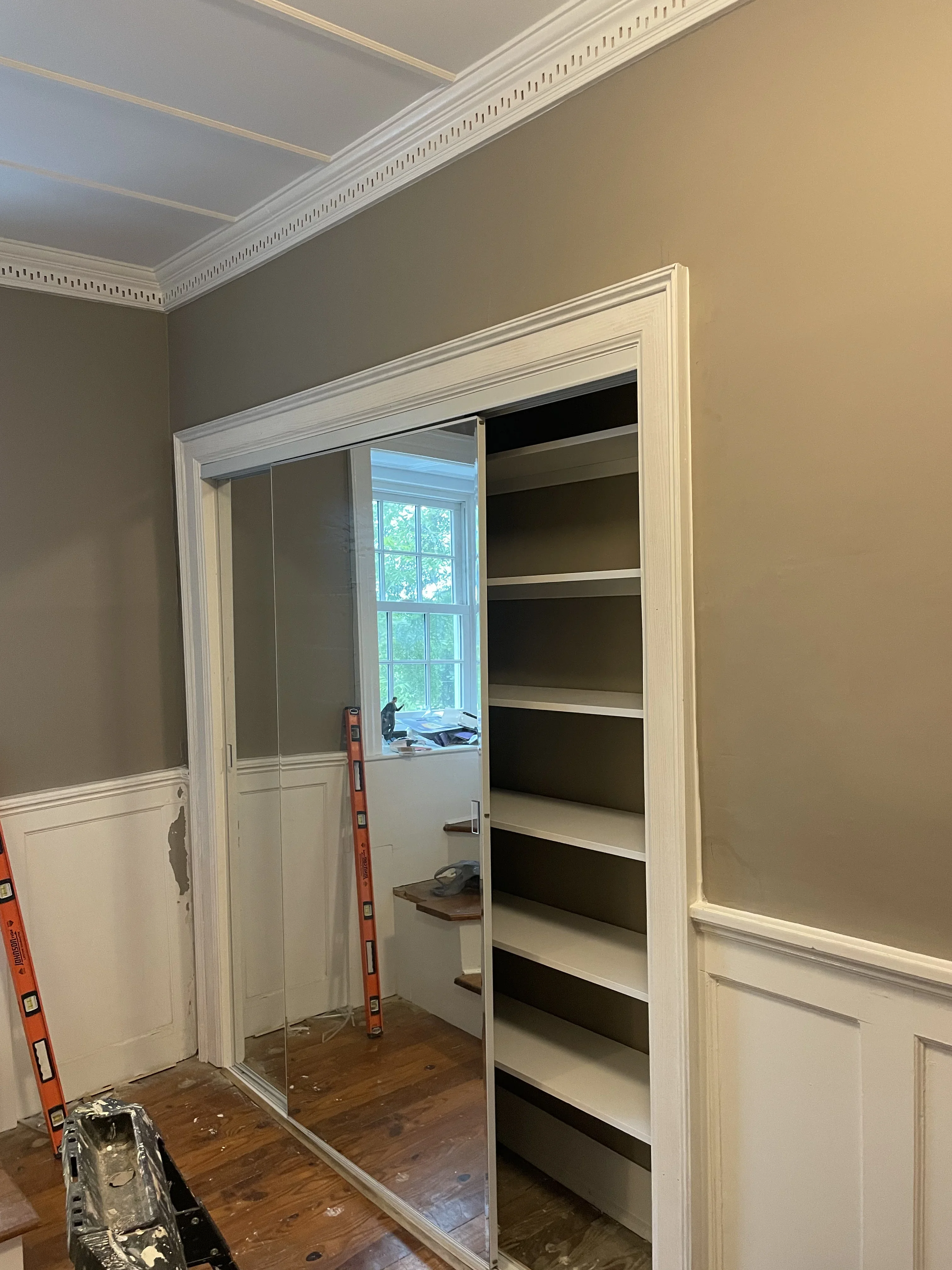 Painted walk-in closet with two-tone walls, white trim, and built-in shelving