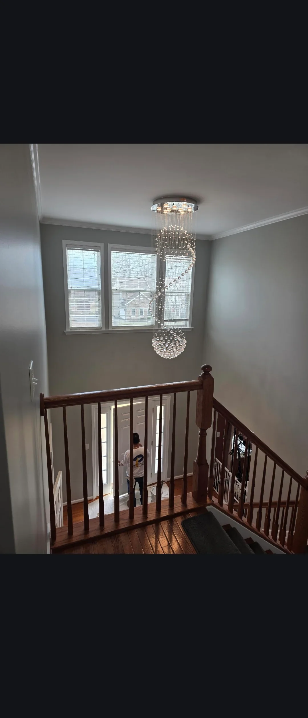 Gray painted stairwell with white trim, dark wood railings, and crystal chandelier fixture