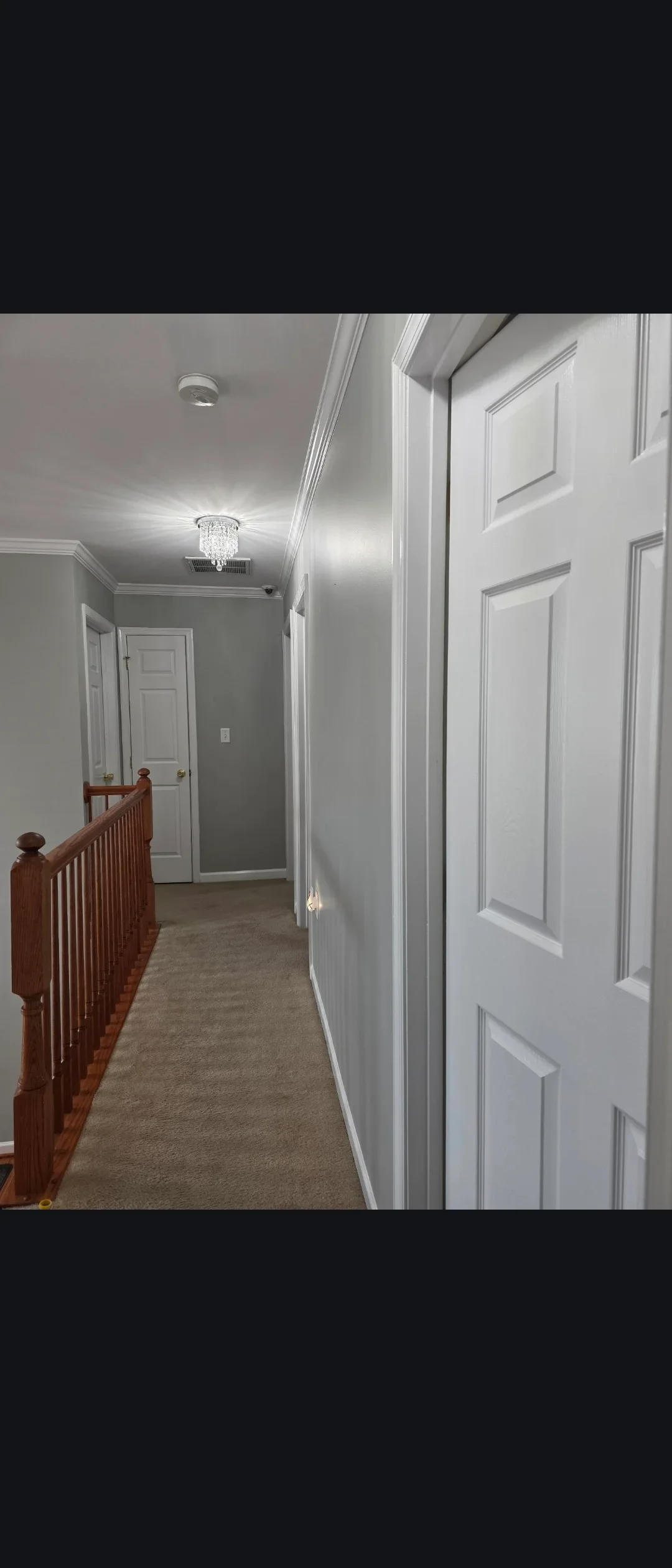 White painted hallway with six-panel doors, crown molding, and recessed lighting fixtures