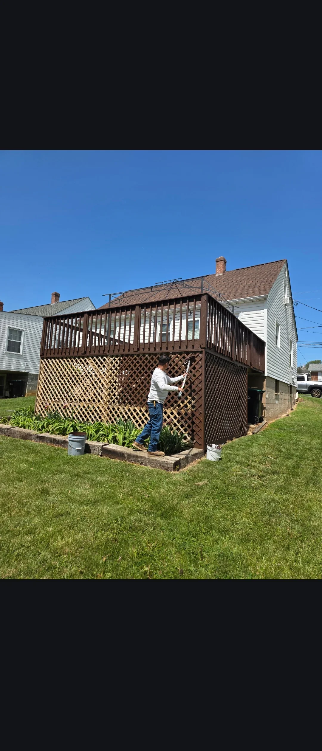 Dark brown stained deck with lattice skirting and vertical railings on residential home