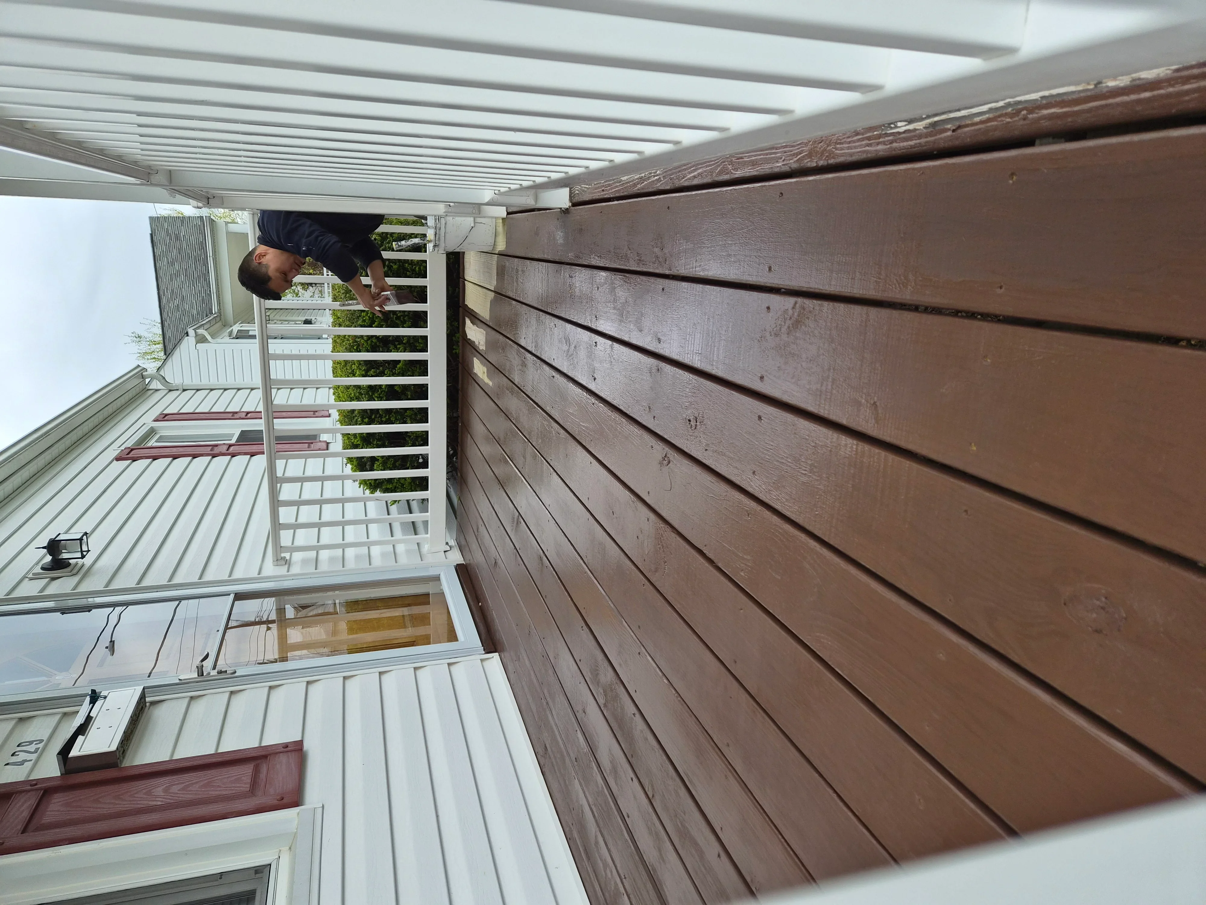 Brown stained horizontal deck boards with white painted trim, railings, and soffit installation