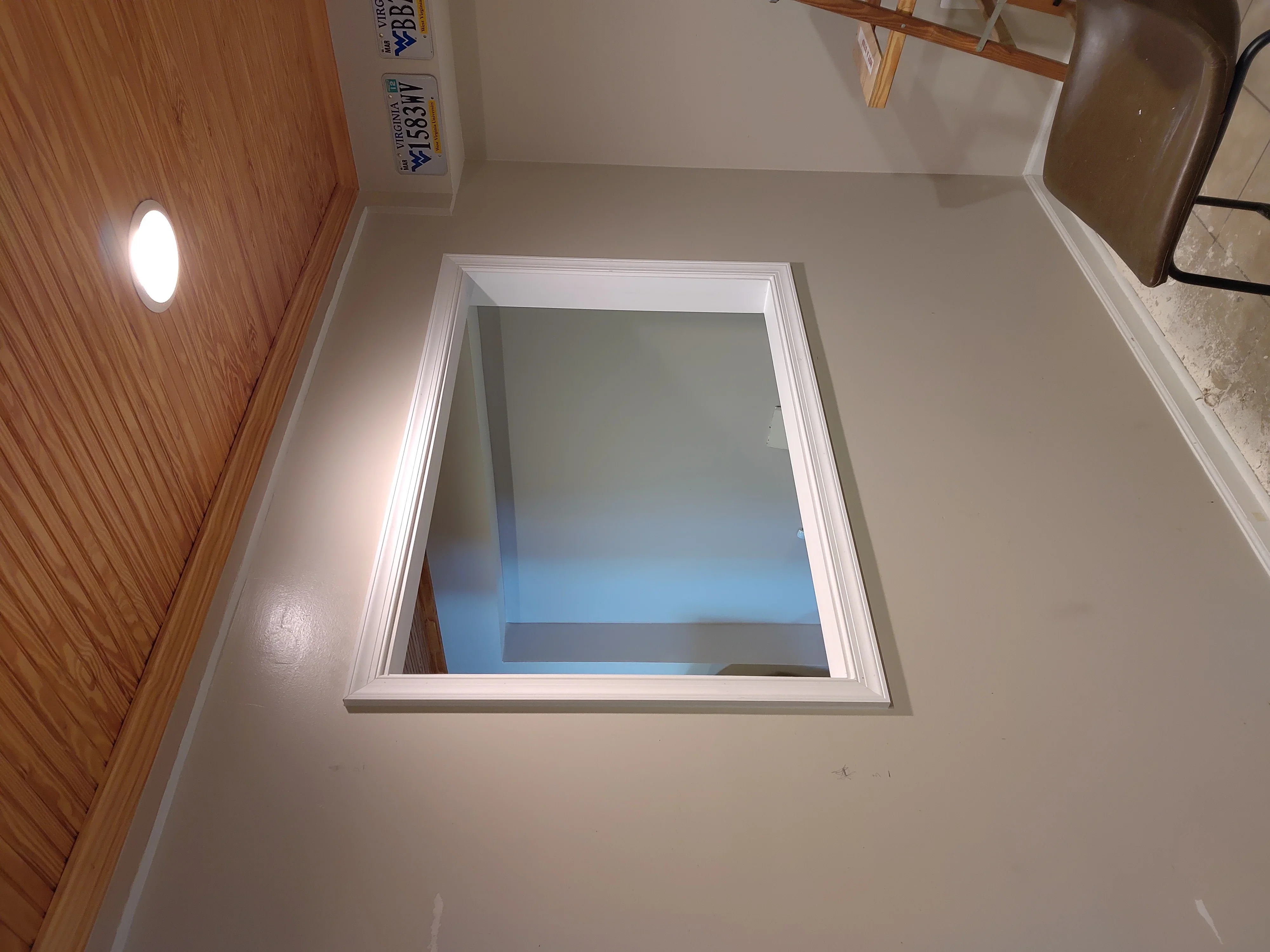 White-trimmed attic access door with recessed lighting in drywall ceiling