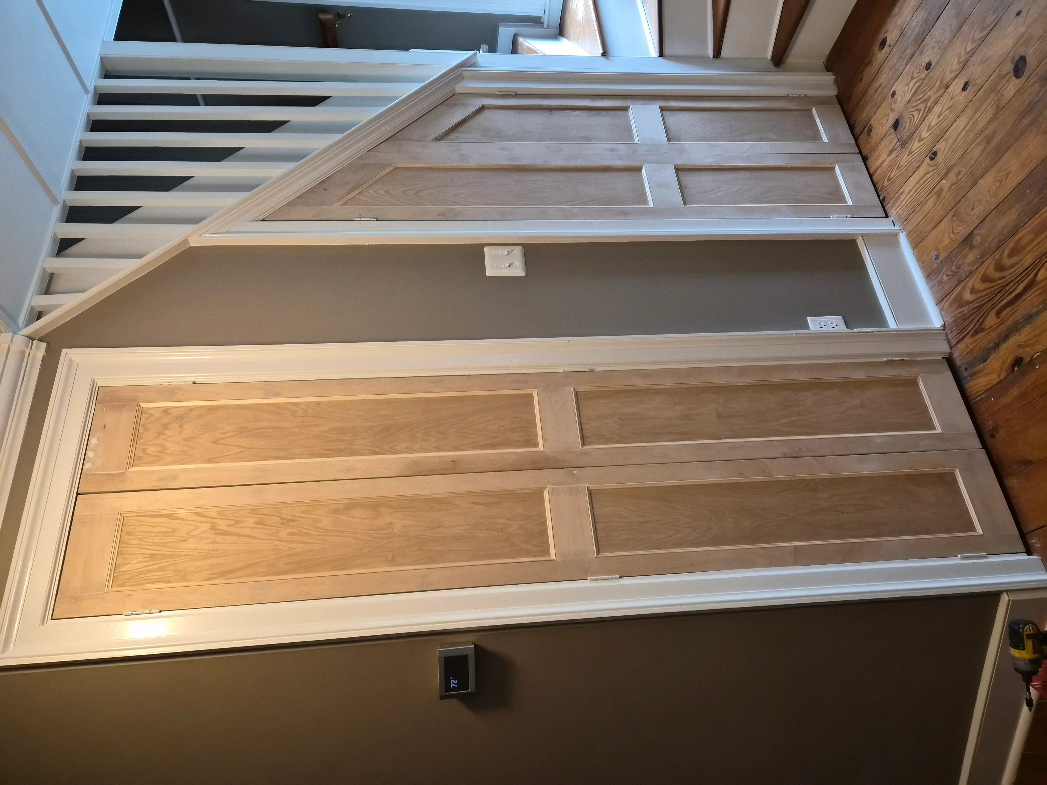 Six-panel wooden door with natural stain and painted white trim and walls