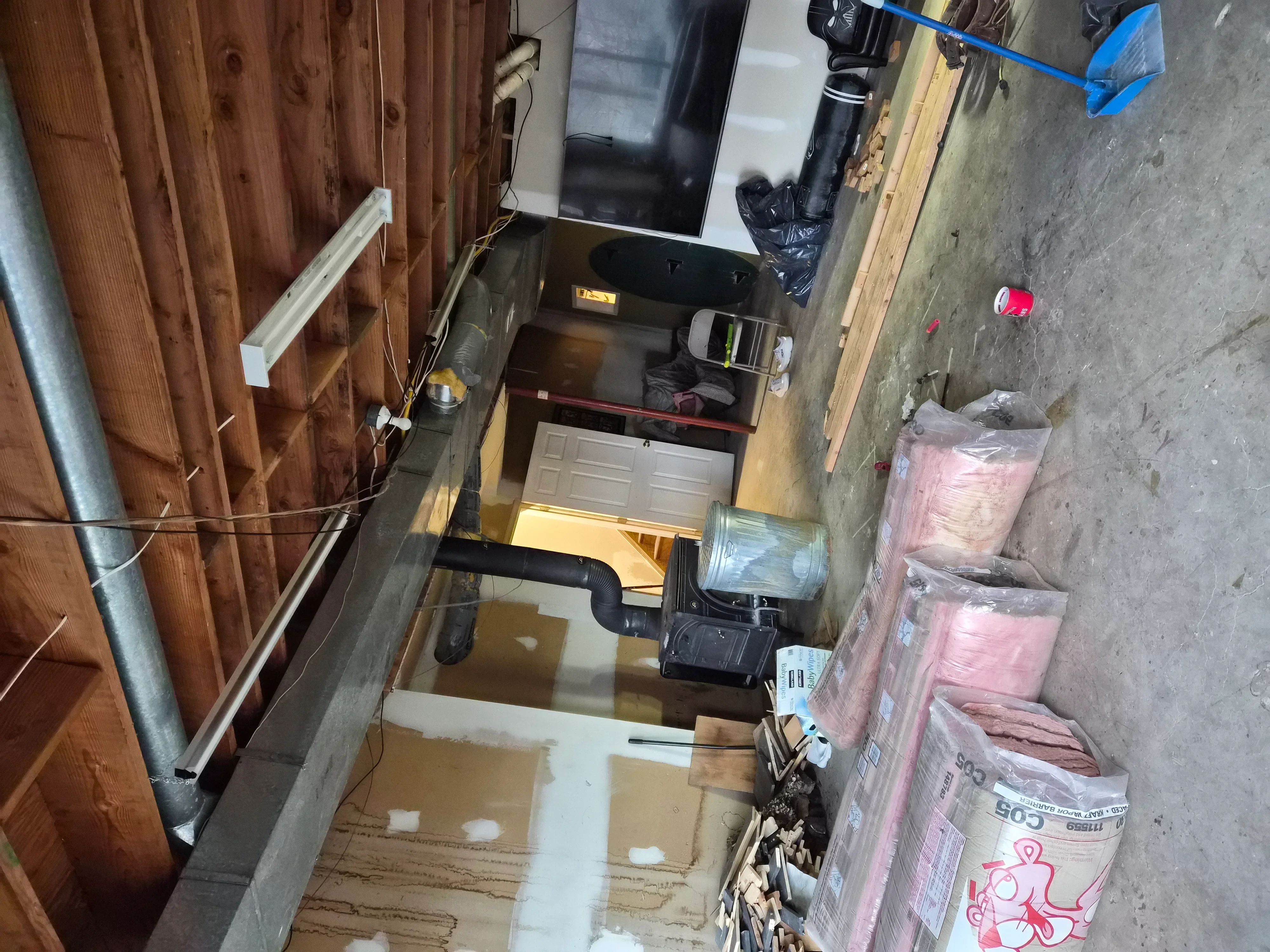 Garage interior with painted walls, drop cloths, masking tape, and insulation materials staged for painting project
