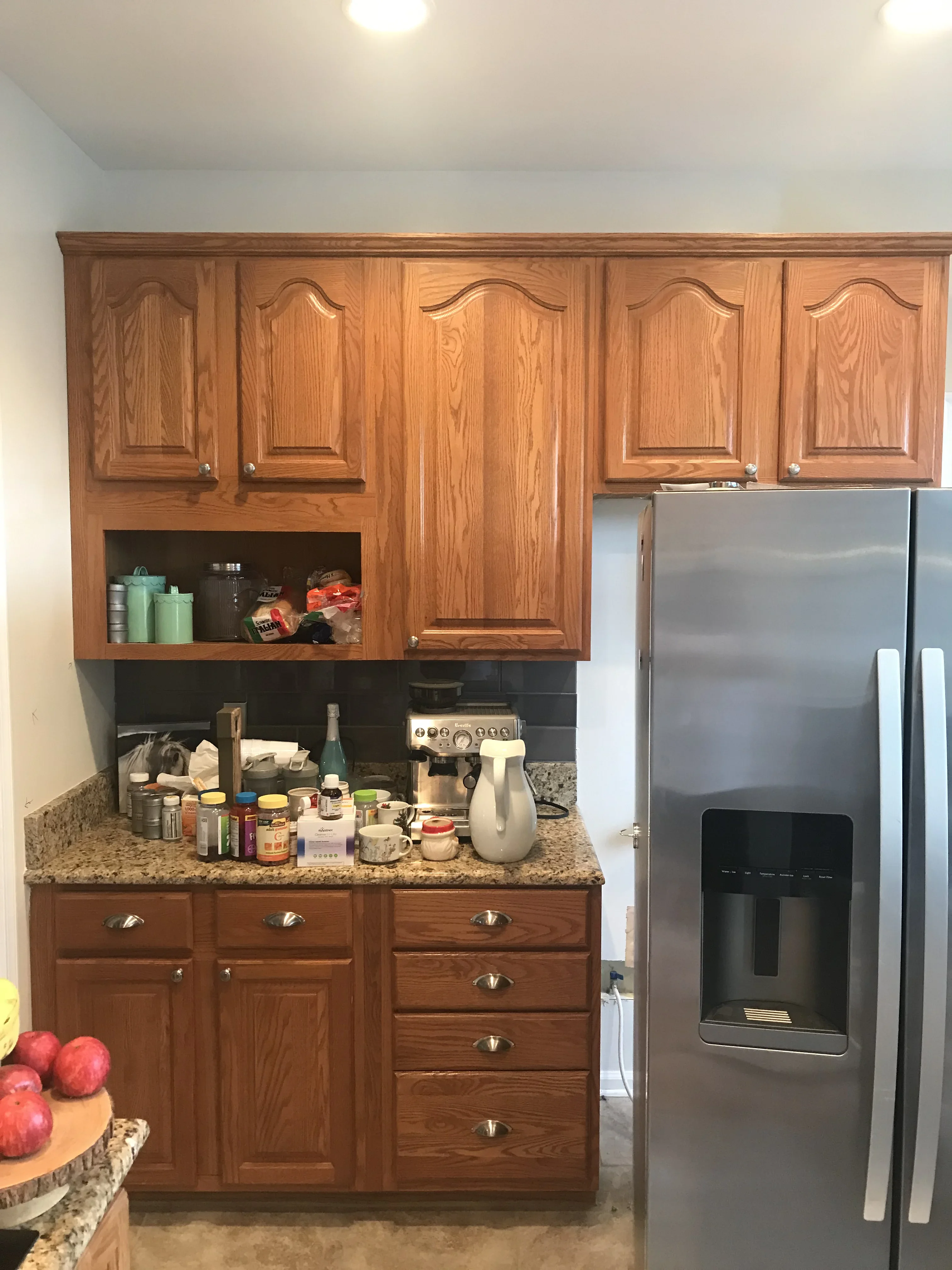 Stained oak kitchen cabinets with black accent wall and granite countertop