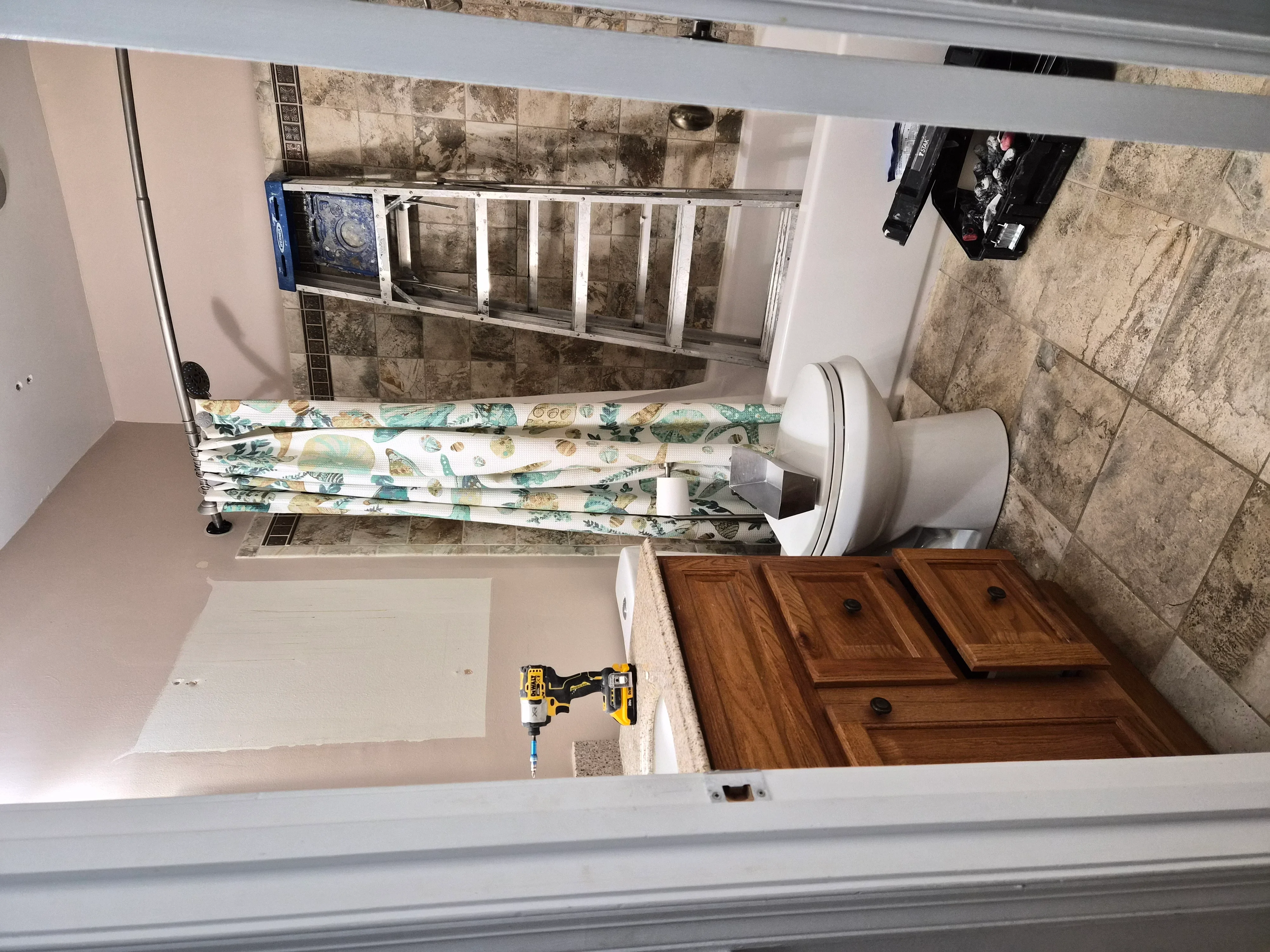 Bathroom with white painted walls, ceramic tile backsplash, wooden vanity, and new fixtures during renovation