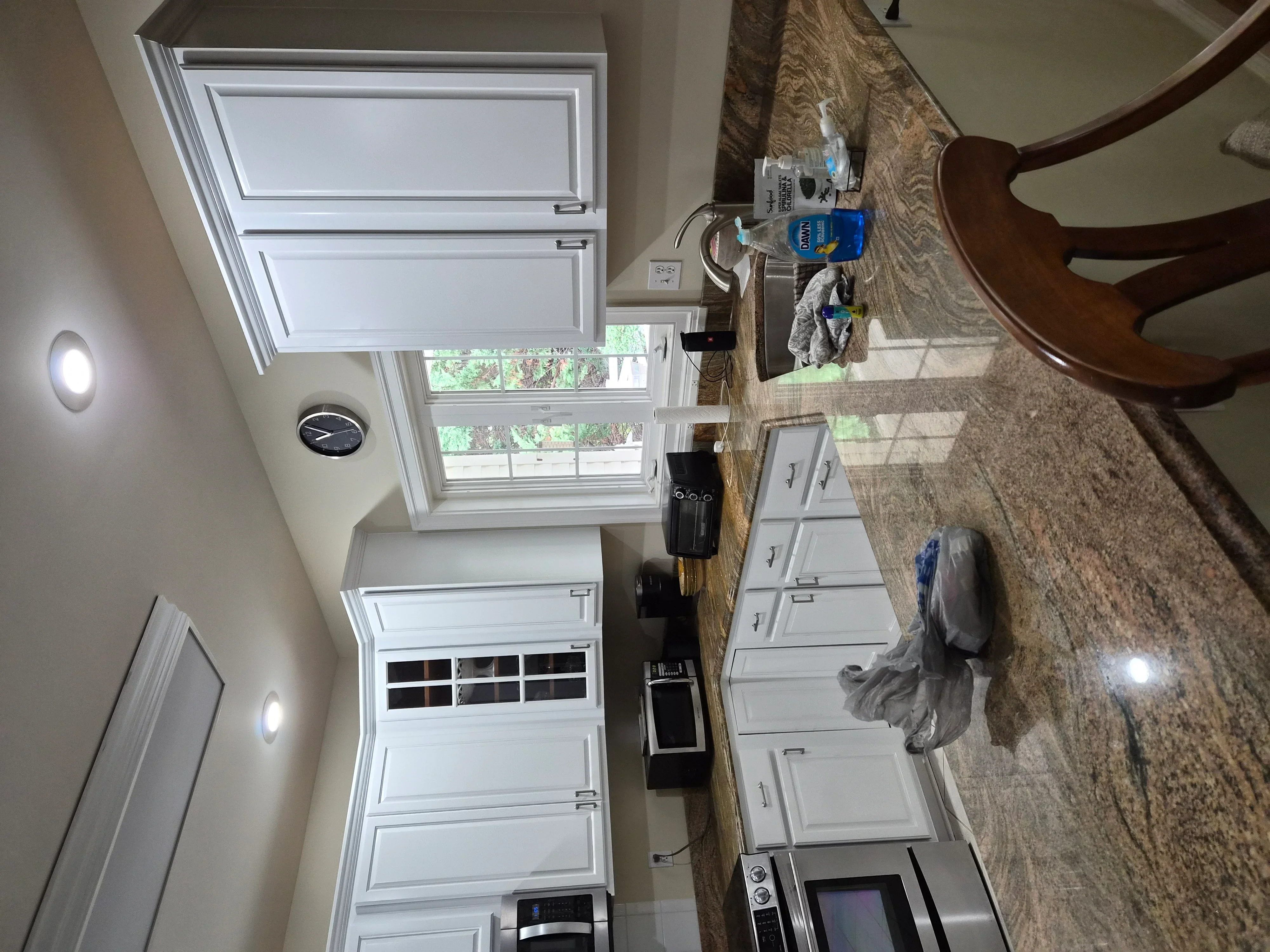 White painted kitchen cabinets, walls, and ceiling with recessed lighting and granite countertops