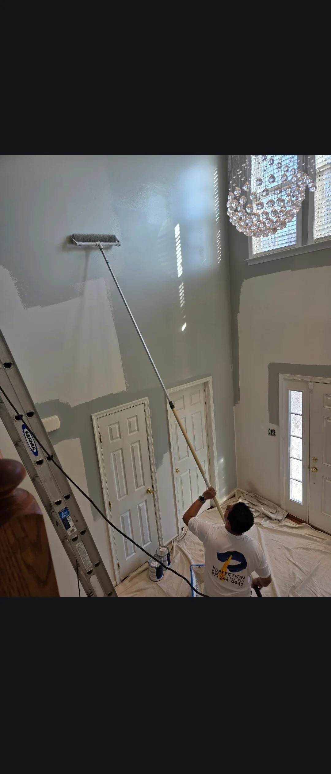 Worker applying primer to drywall walls with roller extension pole in residential interior