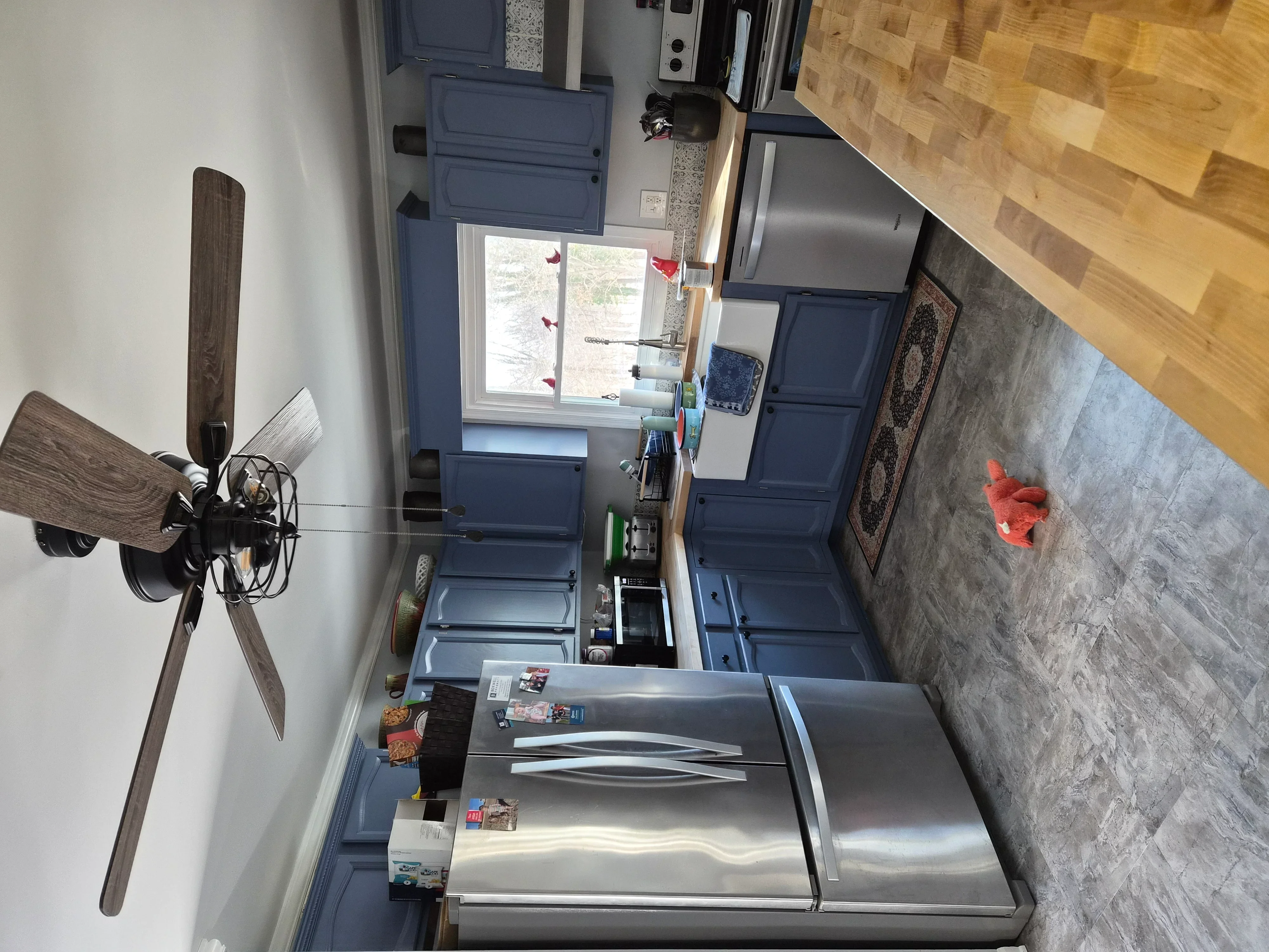Navy painted kitchen cabinets with stainless steel appliances and concrete-finish walls