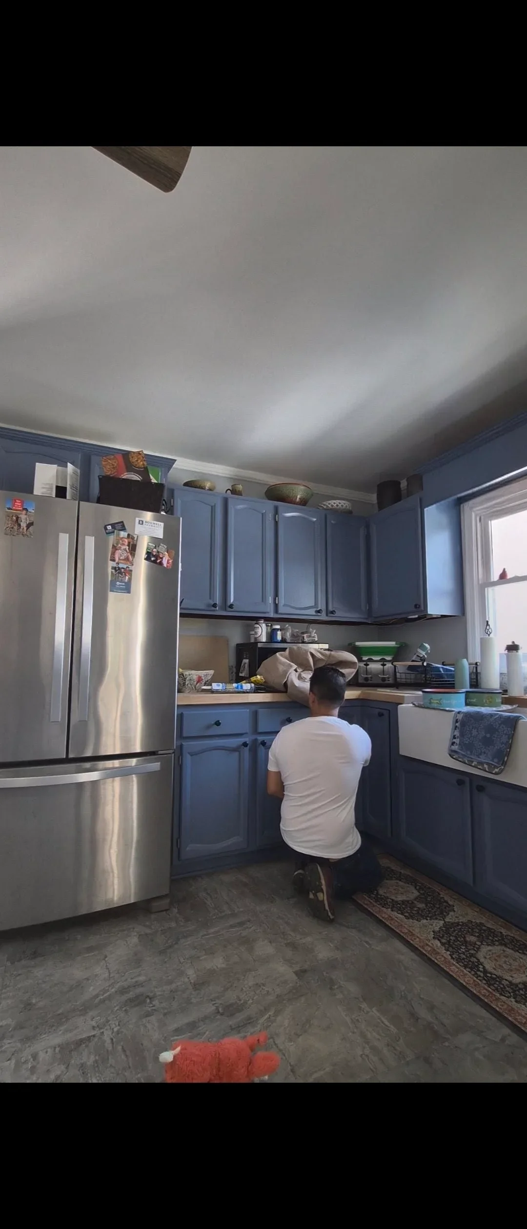 Blue painted kitchen cabinets with stainless steel refrigerator and white ceiling