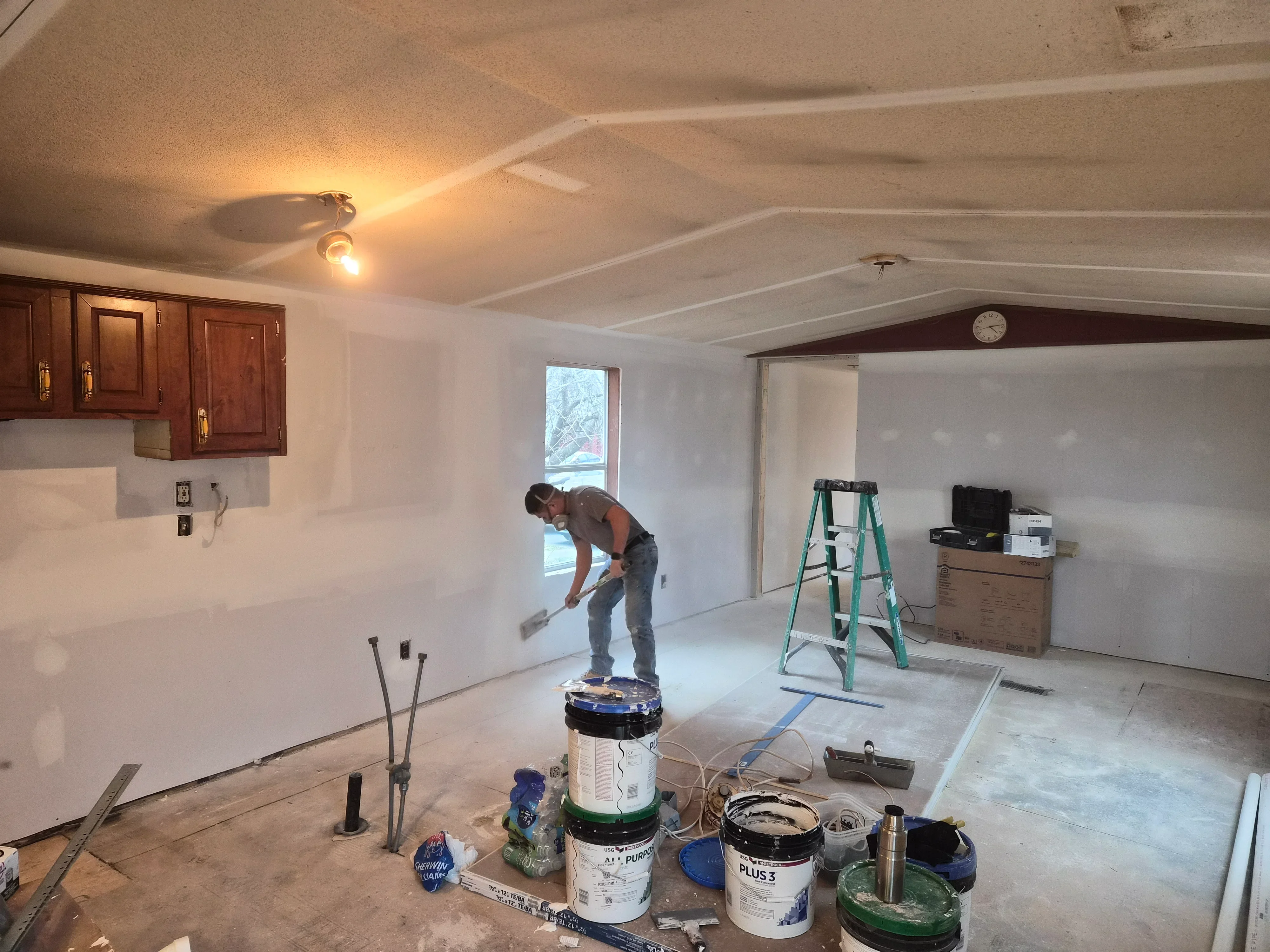 Drywall finishing work with mudding, taping, and primer application on interior walls and textured ceiling