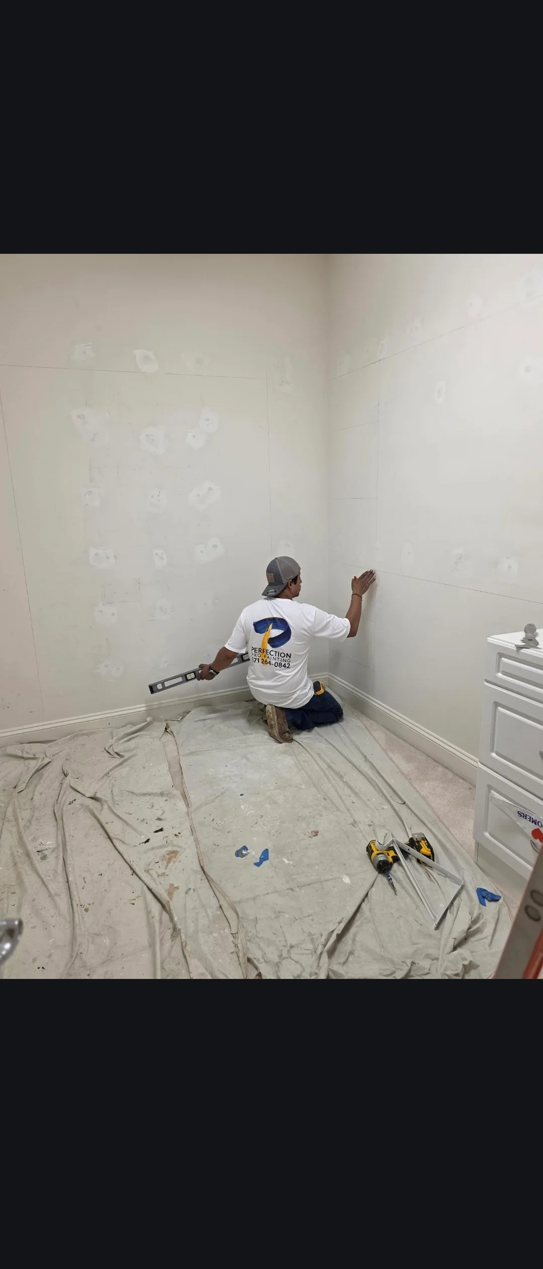 Worker applying joint compound to drywall seams and fasteners in interior room