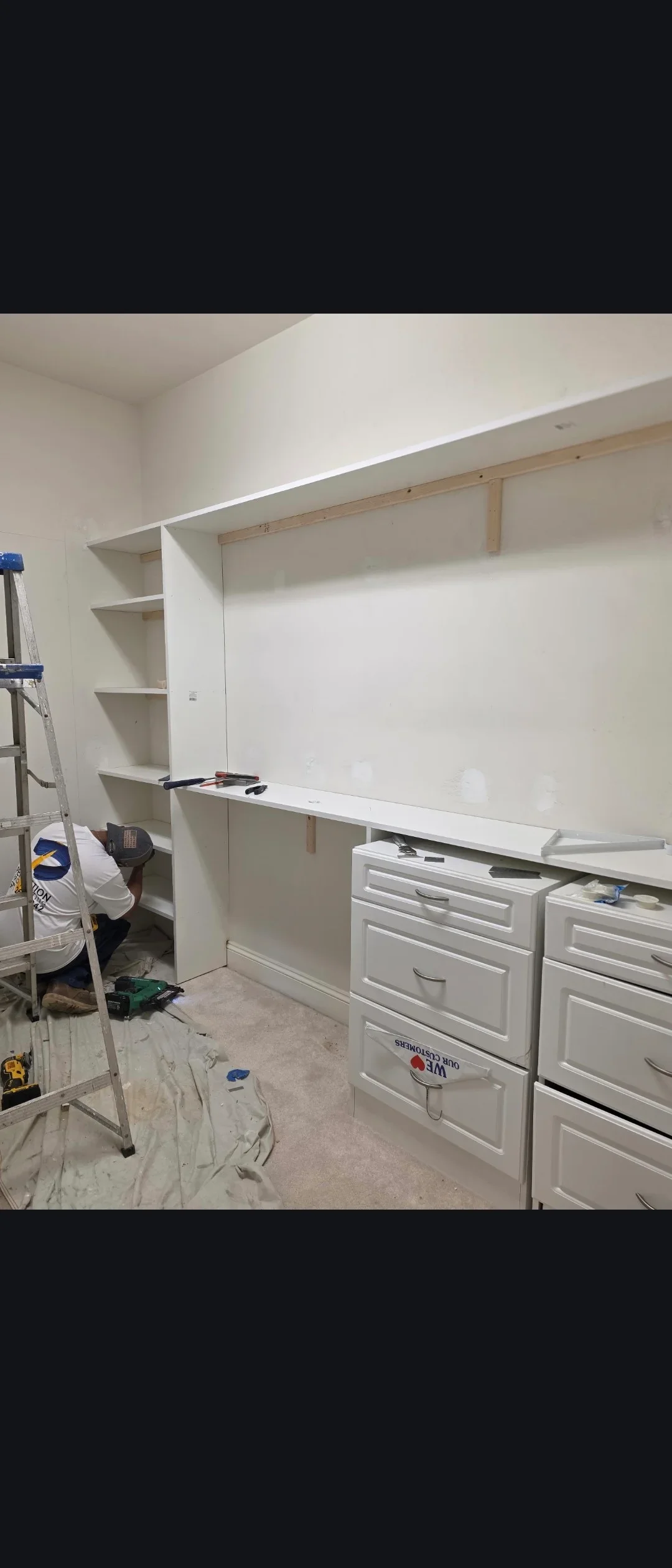 White drywall built-in shelving unit with open shelves and lower cabinet workspace during installation