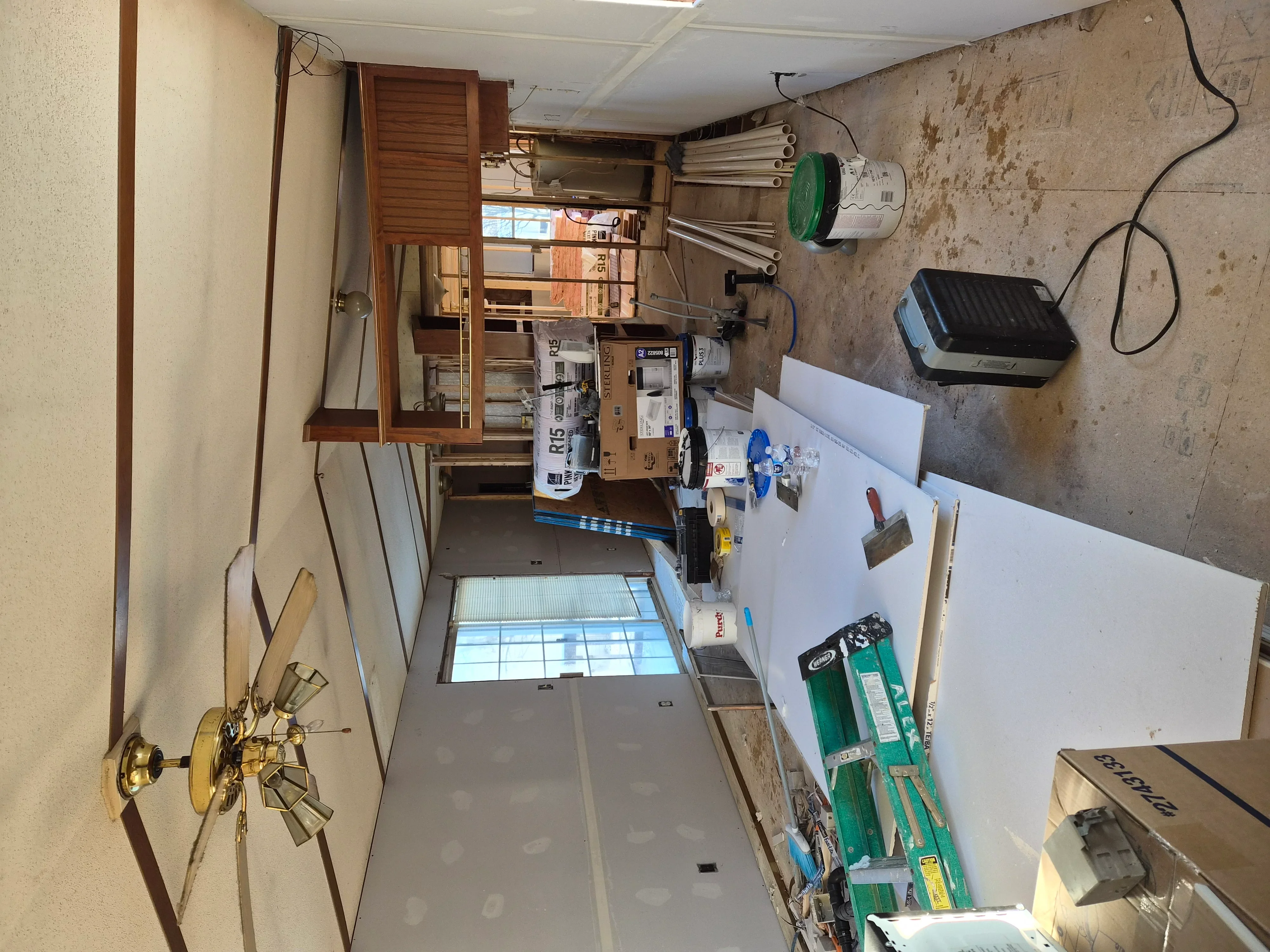 Drywall sheets installed on walls and ceiling with protective coverings and work materials in preparation