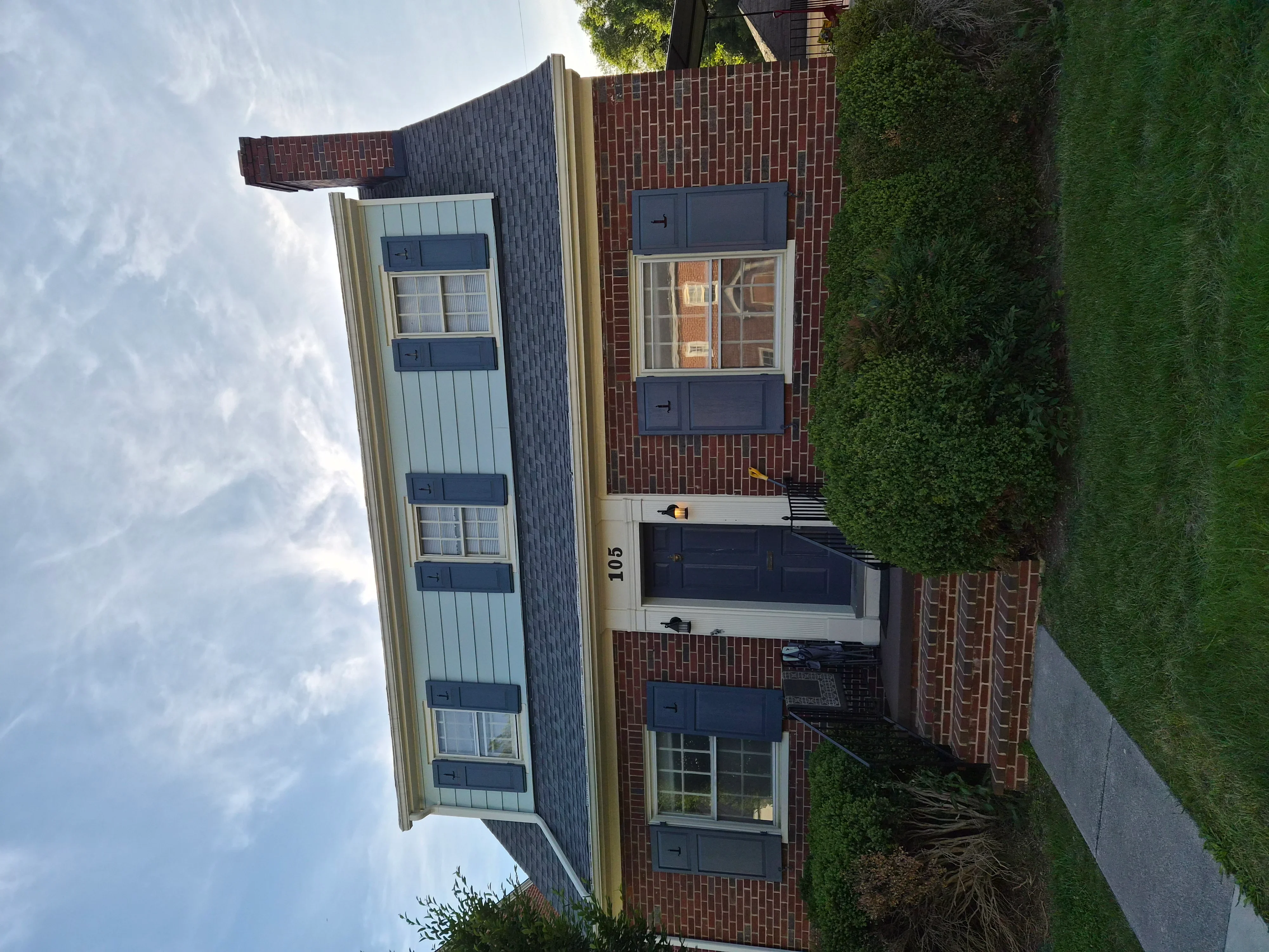 Multi-story building with light blue metal siding and dark blue trim painted on windows and doors