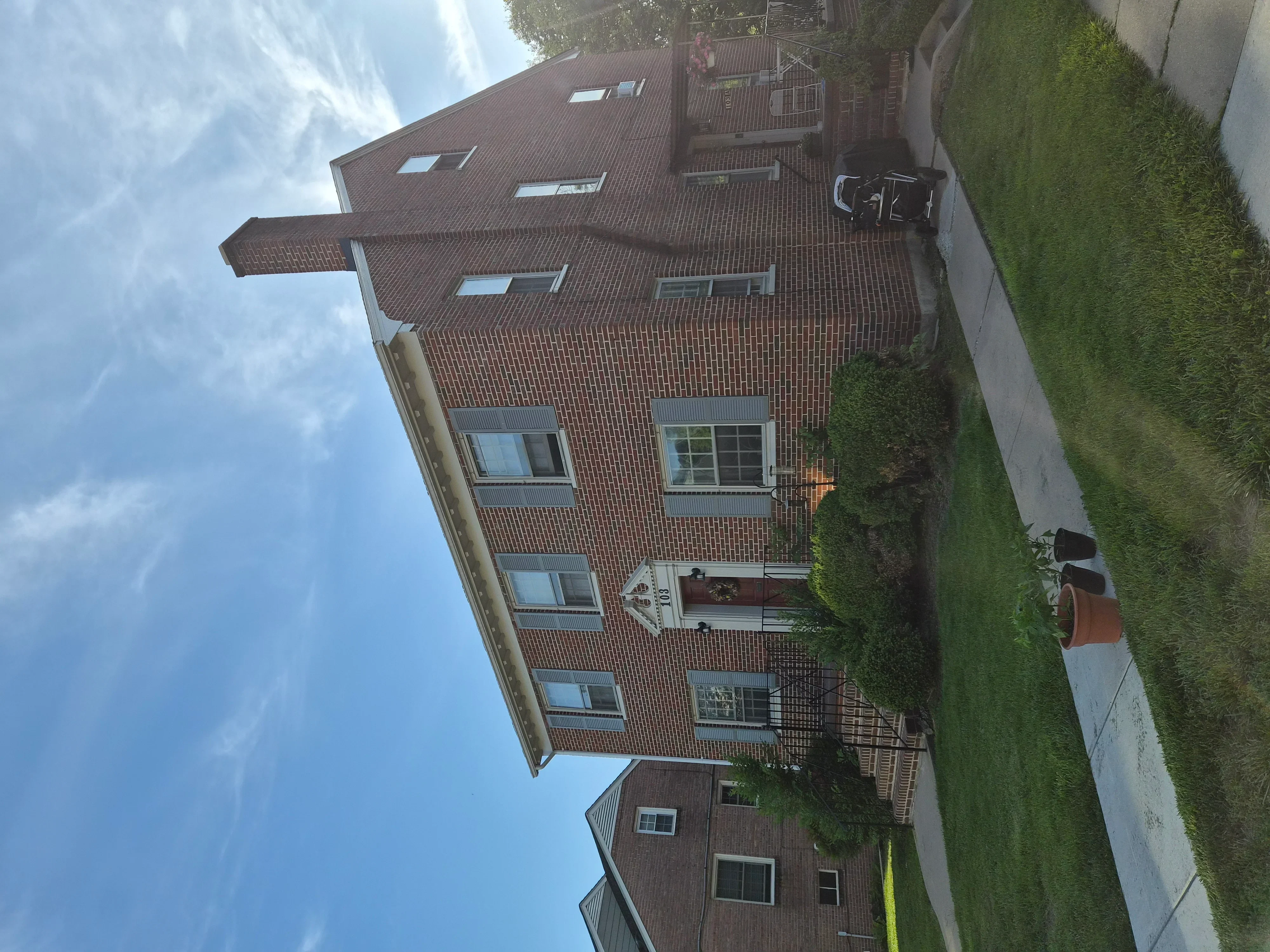 Multi-story brick home with painted exterior, multiple windows, and dormers