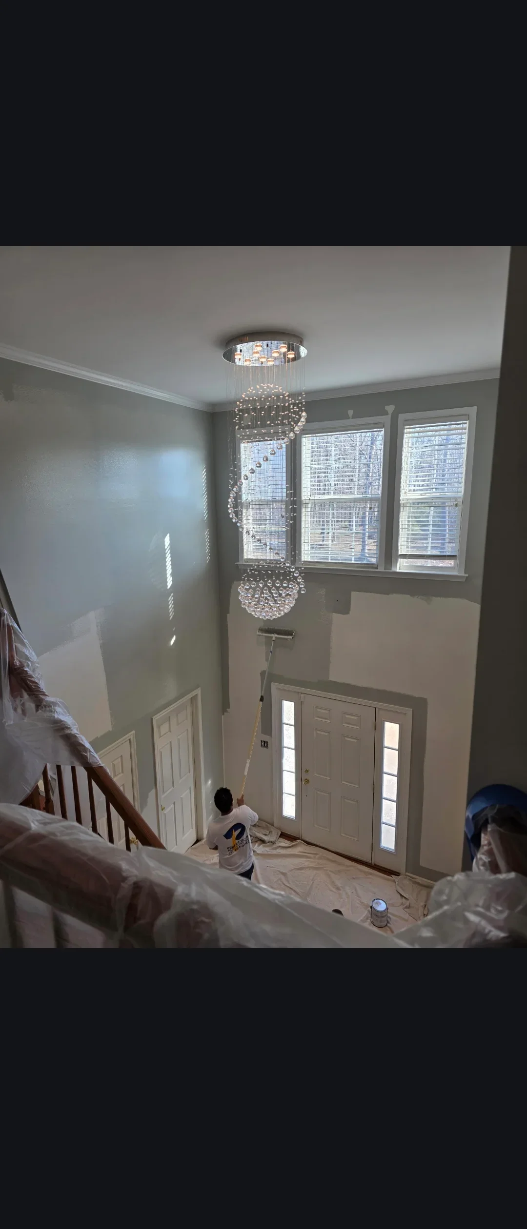 Two-story foyer with gray and cream painted walls, white trim, and crystal chandelier
