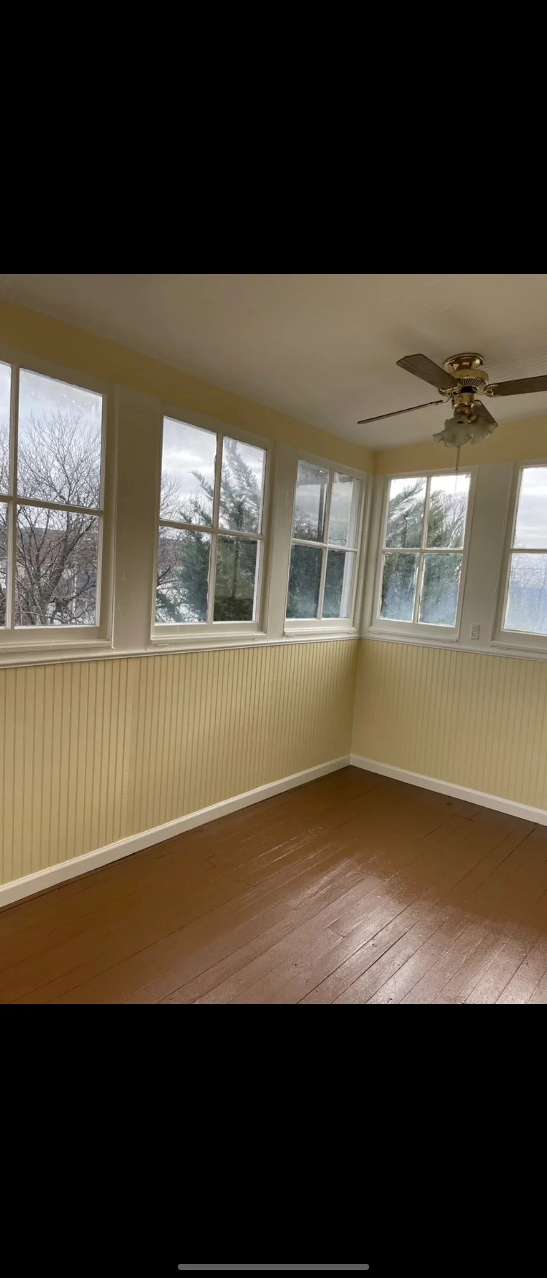 Yellow painted sunroom with white beadboard wainscoting, trim, and freshly painted double-hung windows