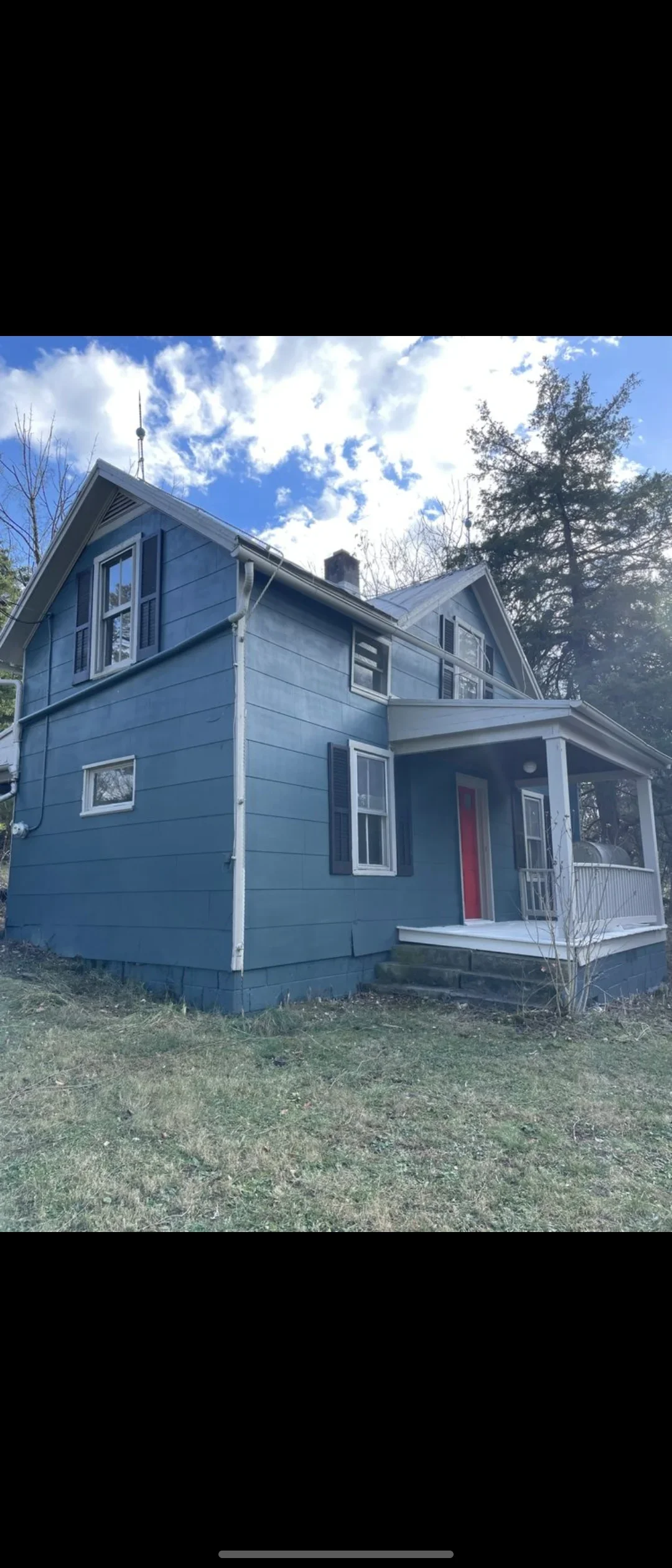 Two-story house with blue lap siding, white trim, and red front door after exterior painting