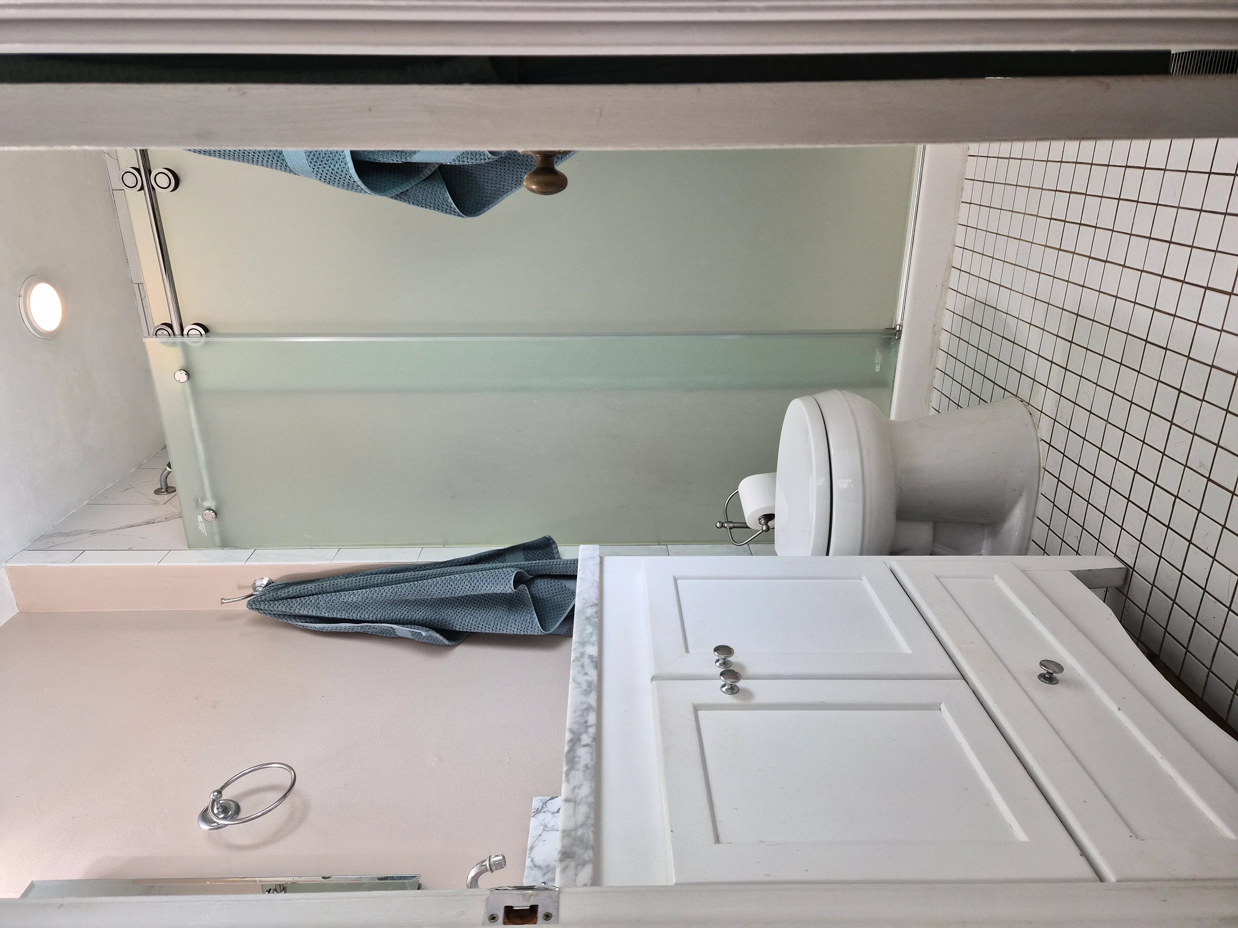 White painted bathroom vanity with panel-front cabinets, marble countertop, and small white tile backsplash