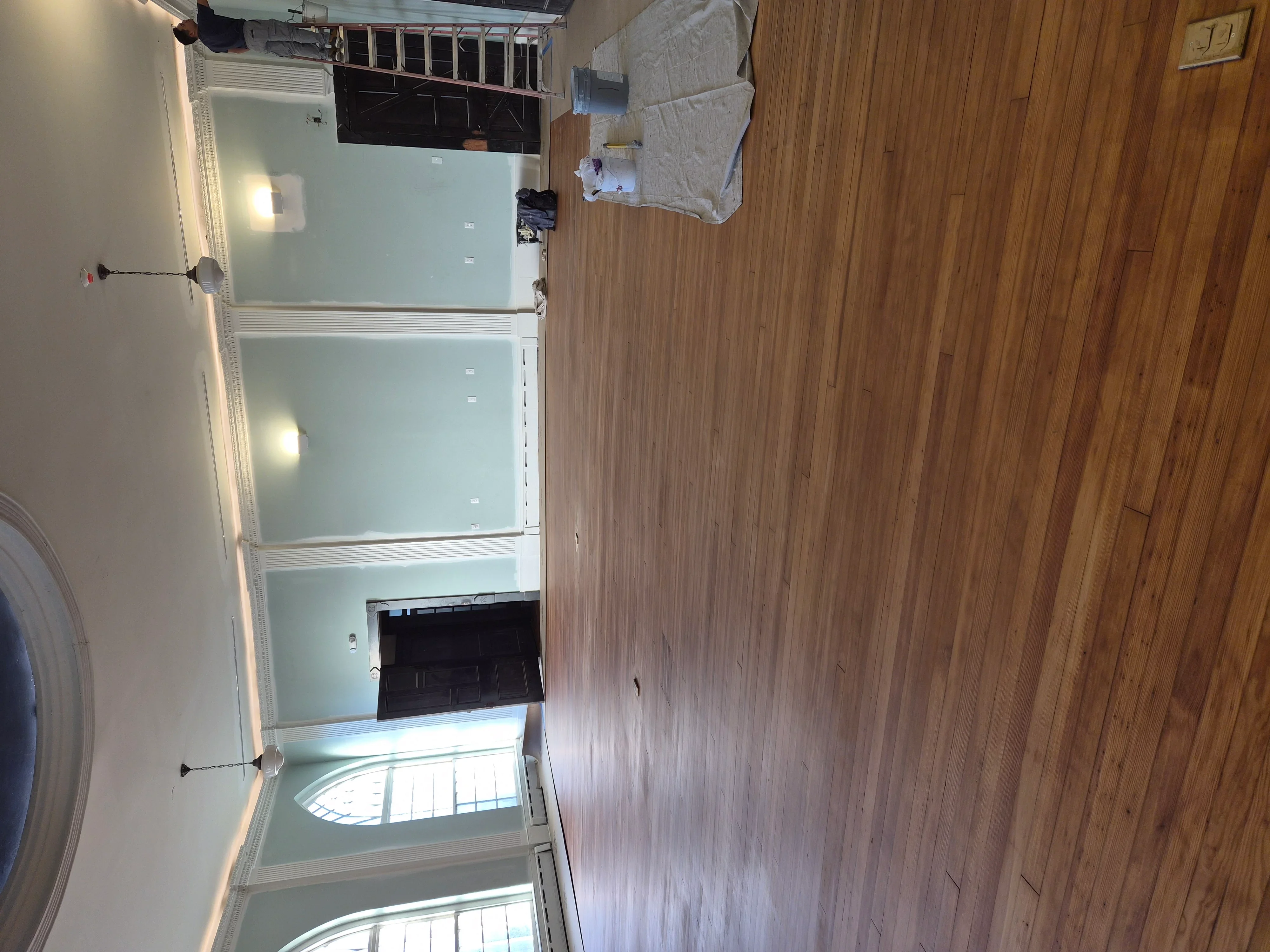 Newly installed drywall with white finish and wood flooring in multi-room interior space