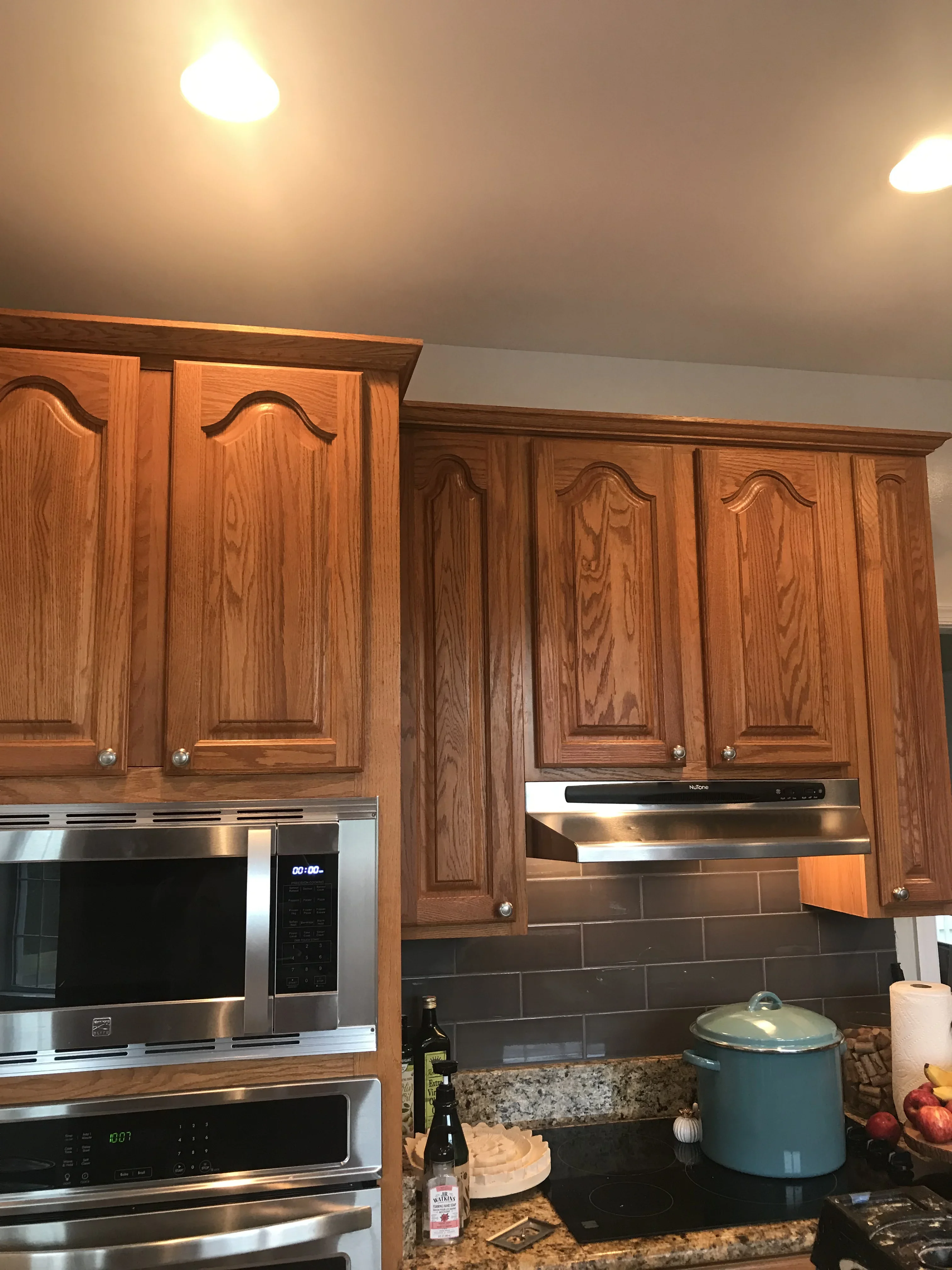 Refinished wood kitchen cabinets with arched panel doors, stainless steel appliances, and granite countertop