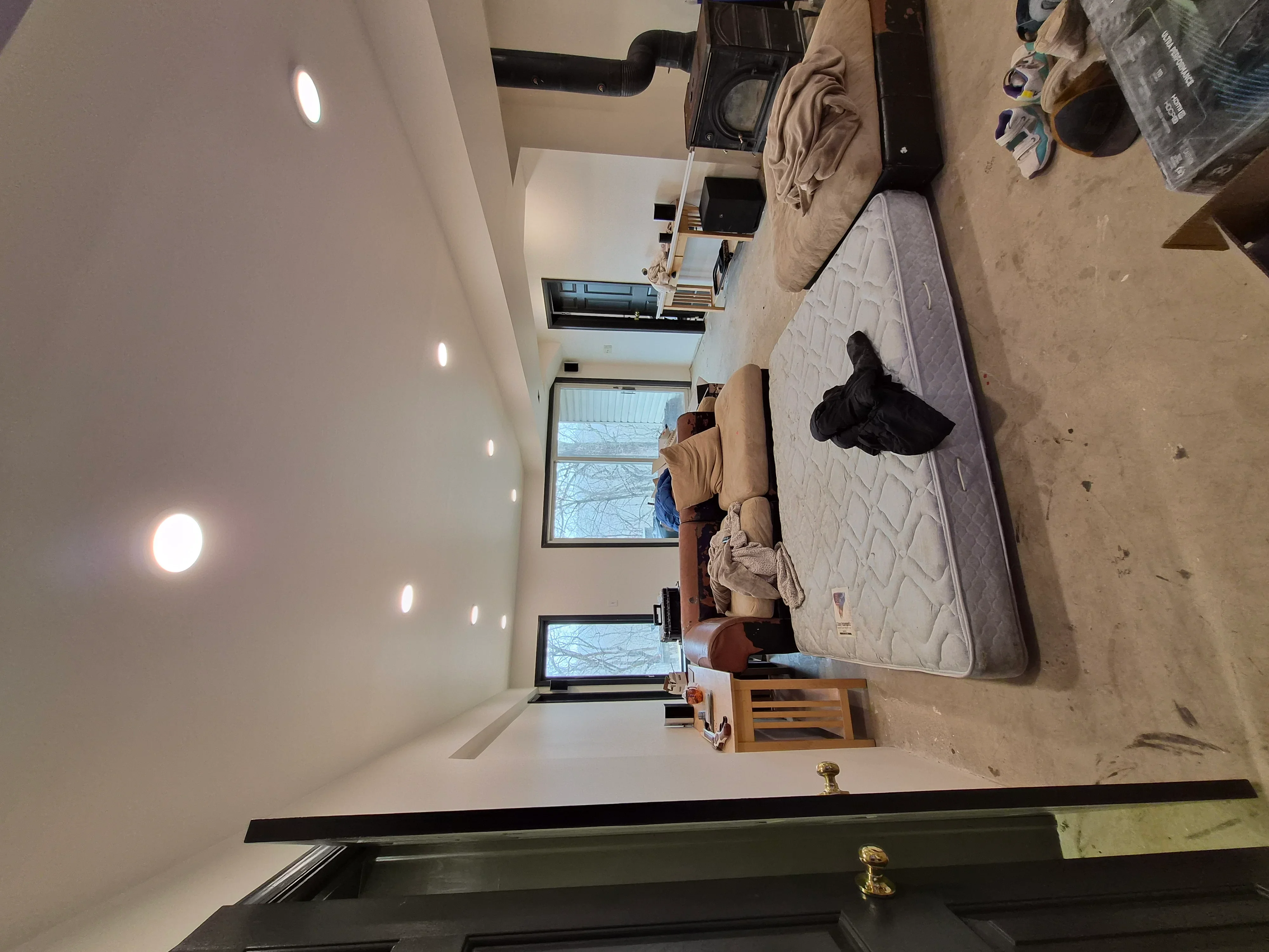 Freshly painted bedroom interior with white drywall walls, recessed ceiling lights, and finished drywall surfaces