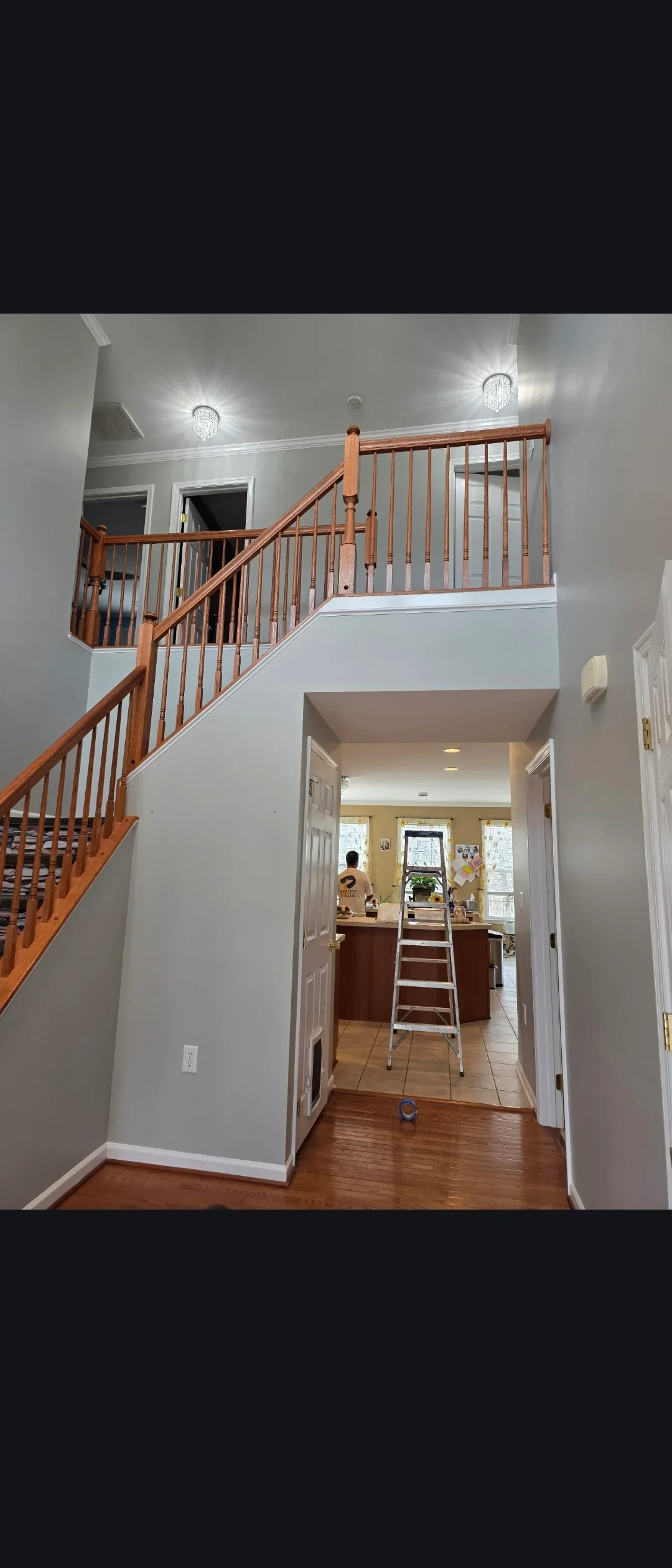 White painted stairwell with wooden handrail, metal balusters, gray ceiling, and white trim in residential interior