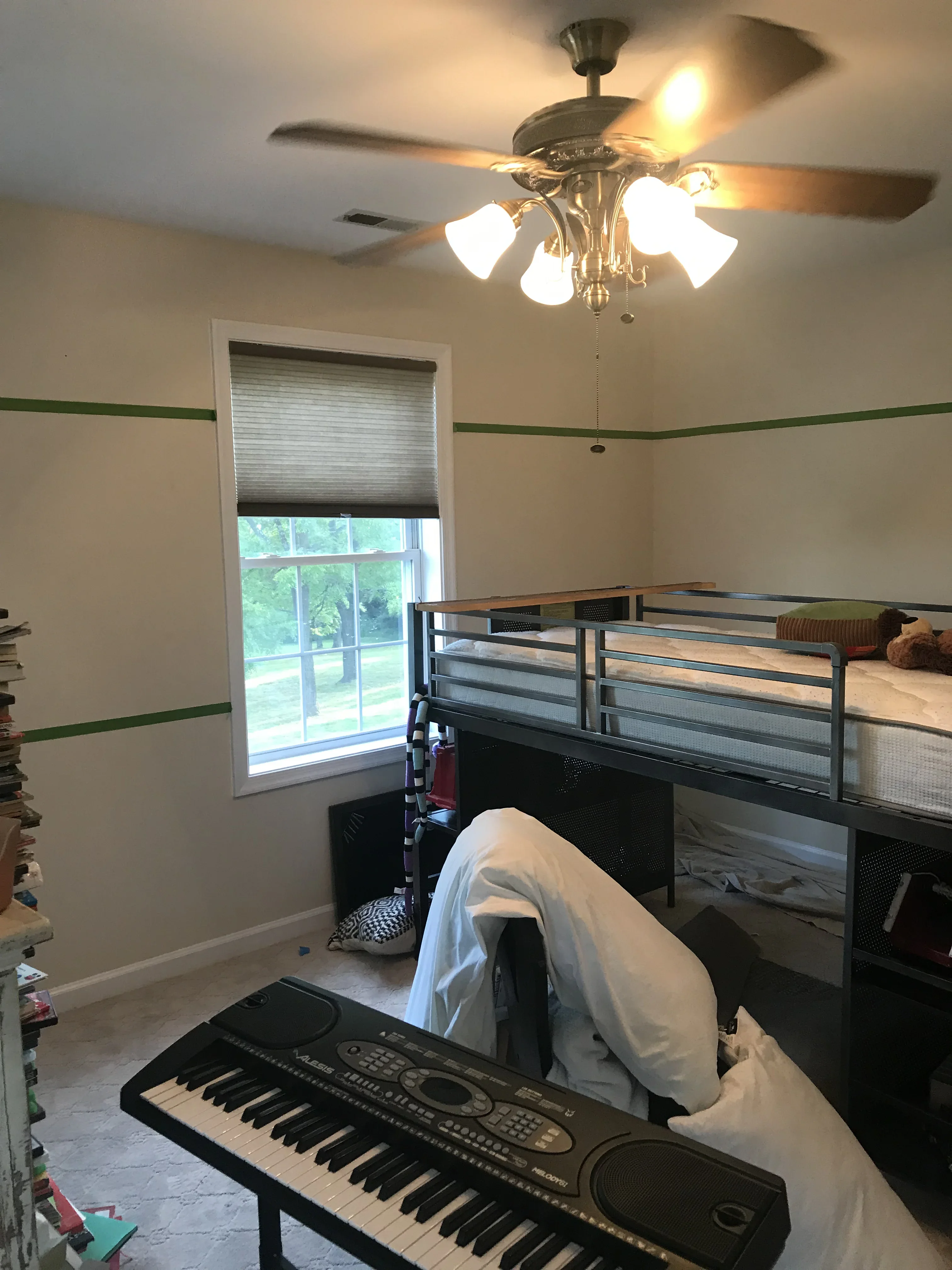 Beige bedroom walls with green accent stripe, white trim, and ceiling fan with light fixtures