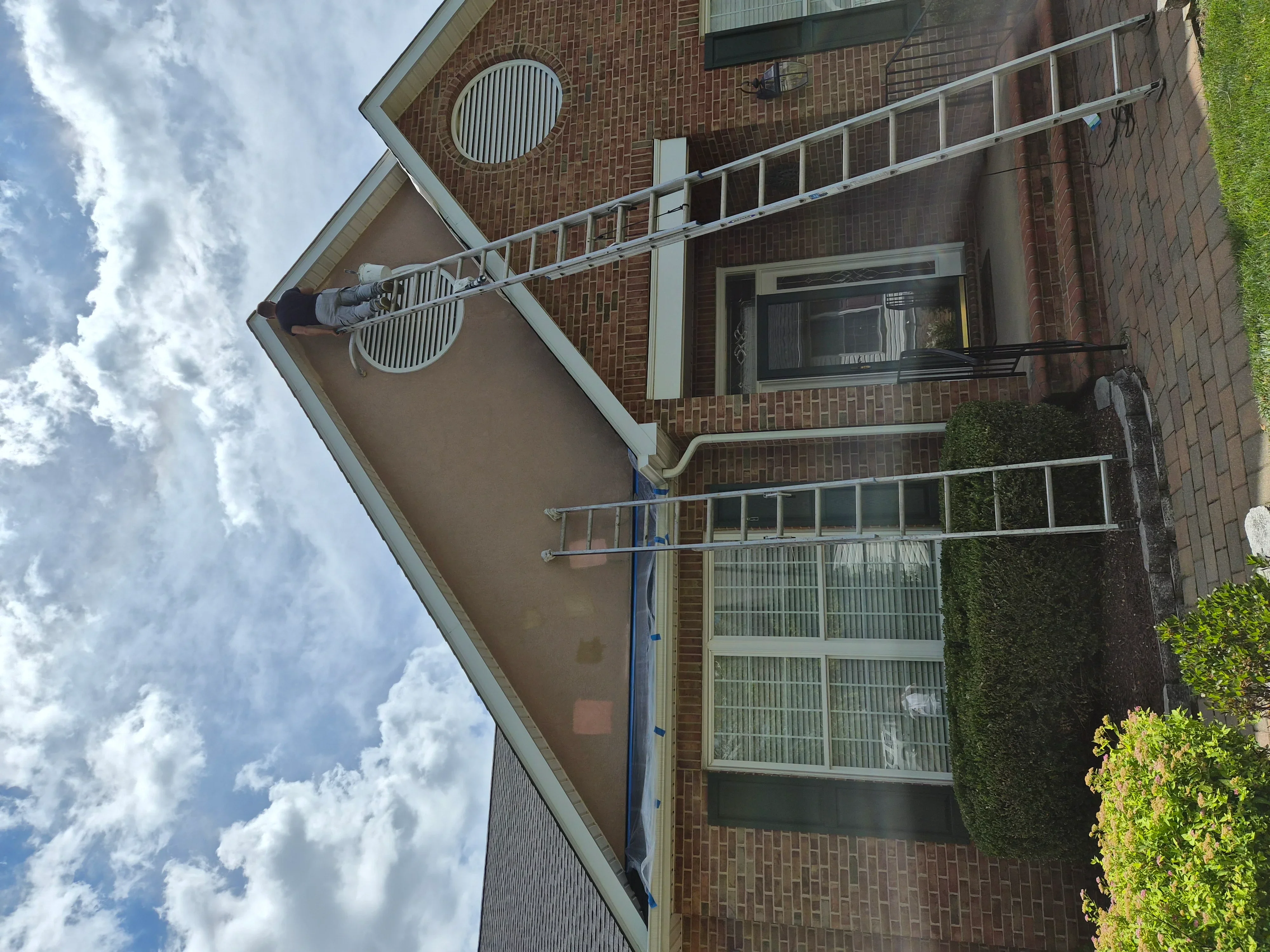 Brick home exterior with painted soffit, fascia trim, and aluminum ladder for access during painting work