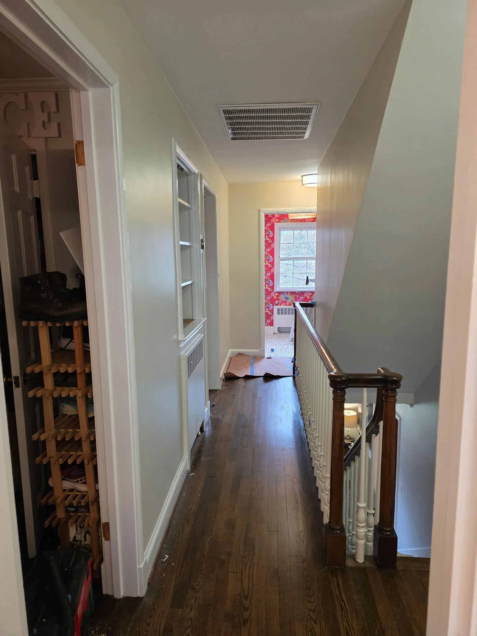 Hallway with neutral painted walls, white trim, dark wood flooring, and staircase with white balusters