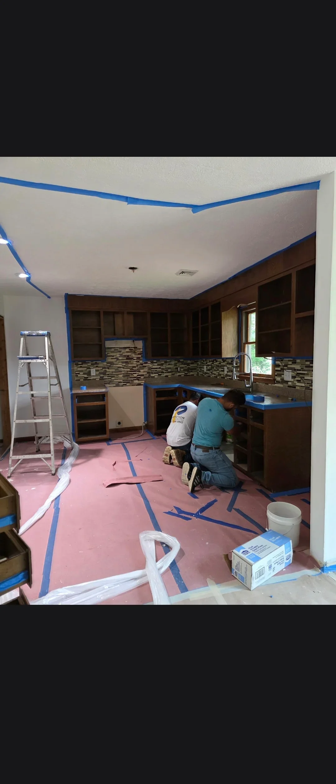 Kitchen renovation with new drywall ceiling, white paint, and blue painter's tape masking