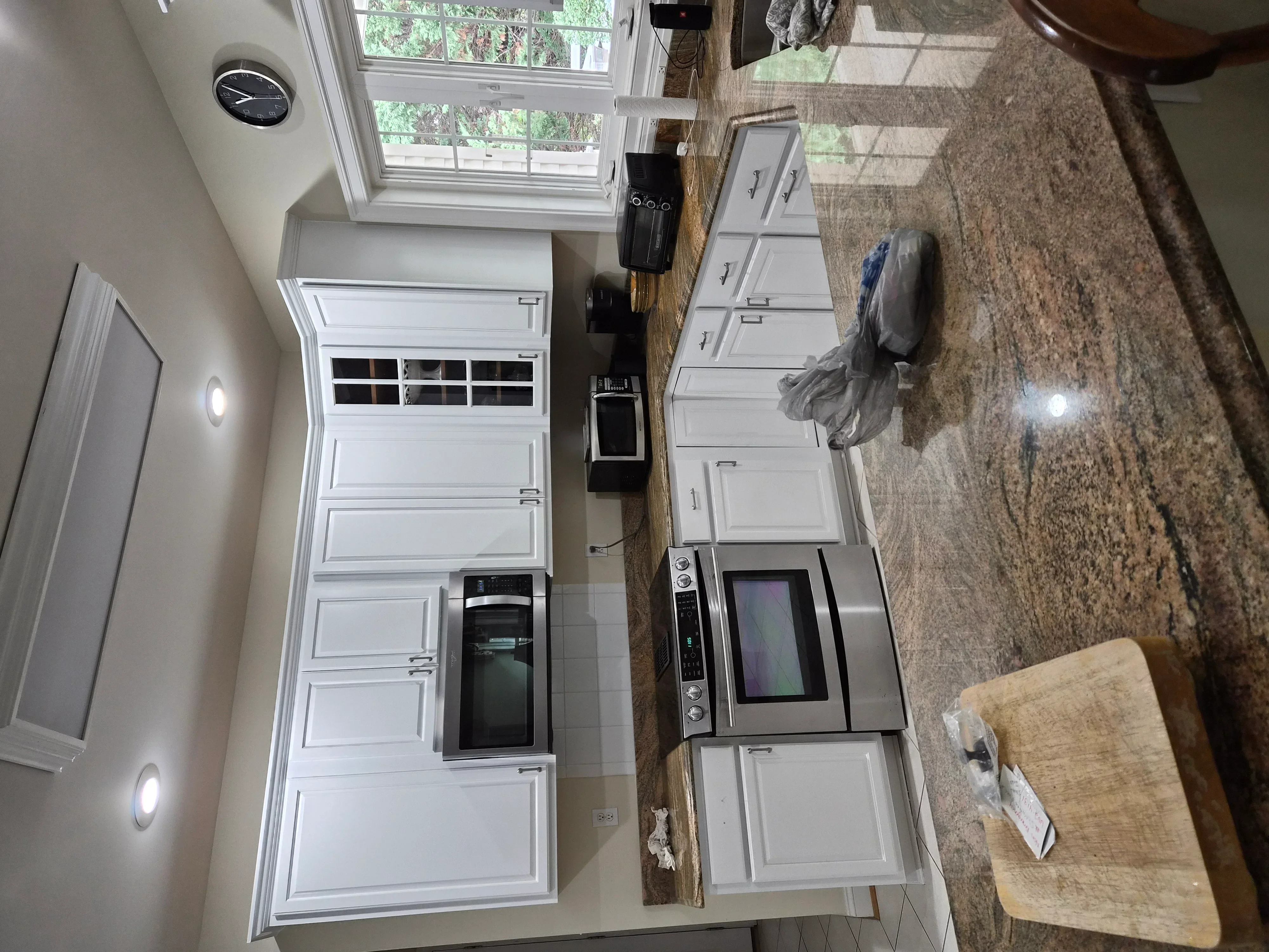 White painted kitchen cabinets with panel details, stainless steel appliances, and granite countertop