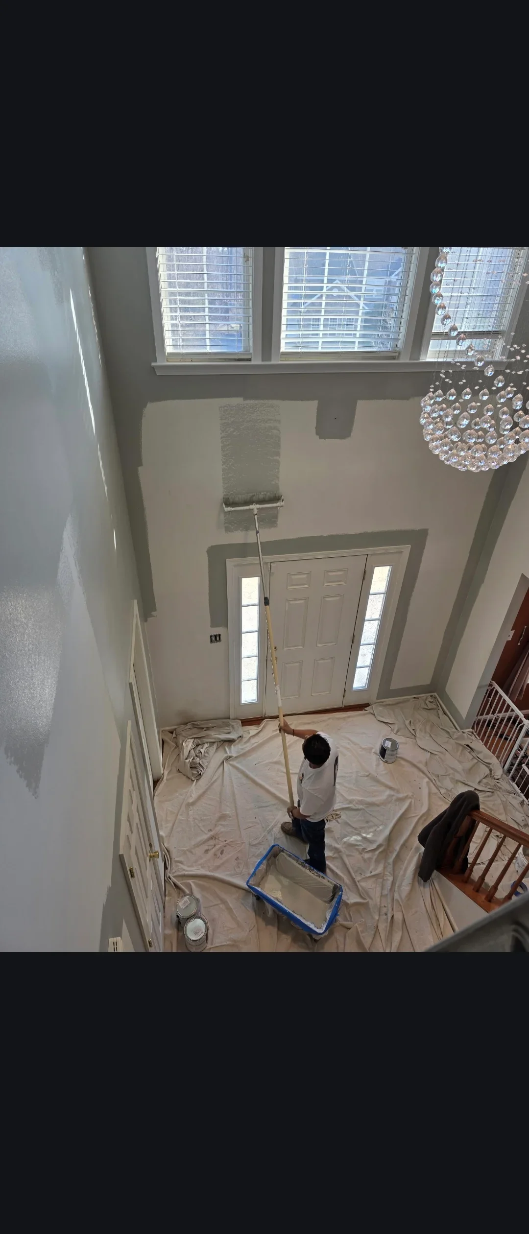 Interior foyer with drywall primer, drop cloths, and high ceilings with windows