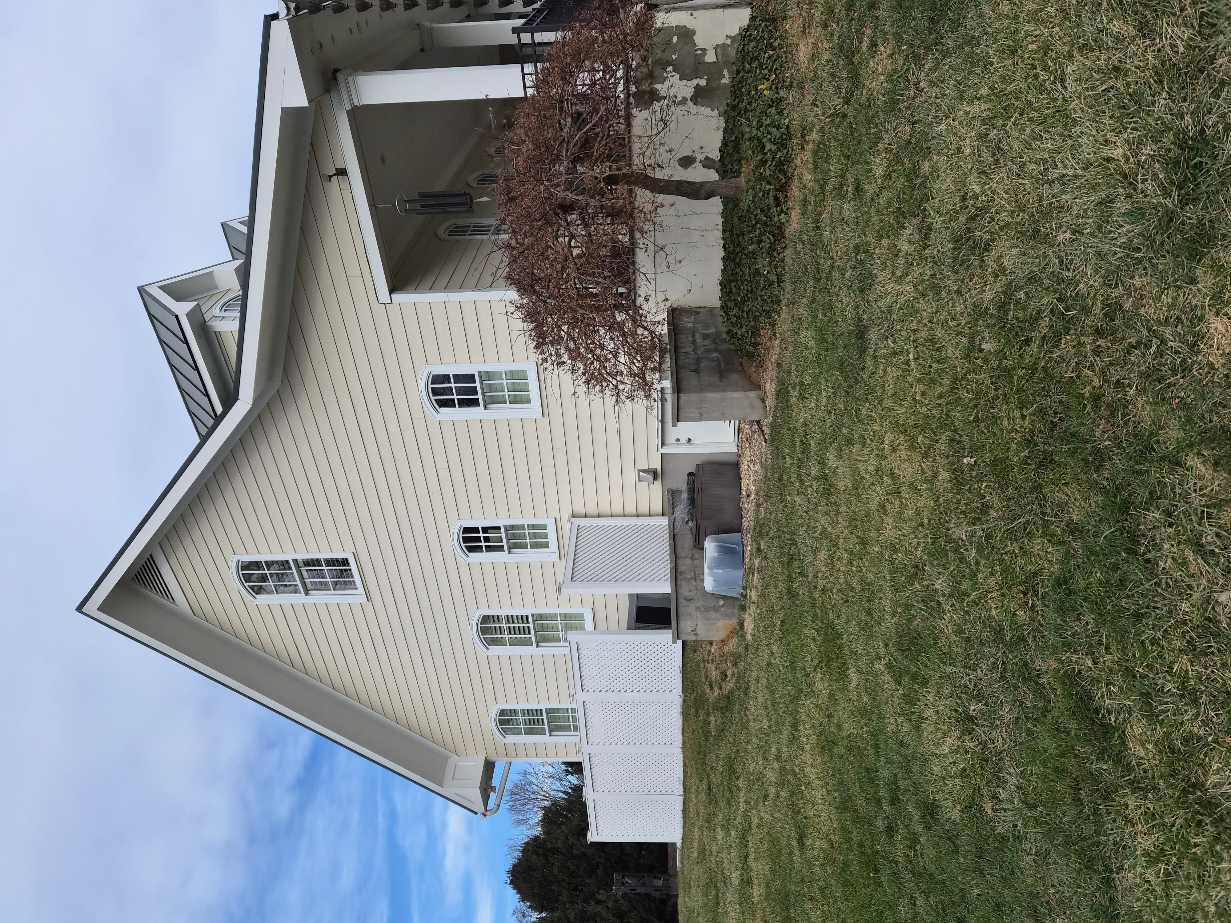 Light gray painted metal siding and roof on residential home with multiple gables and trim