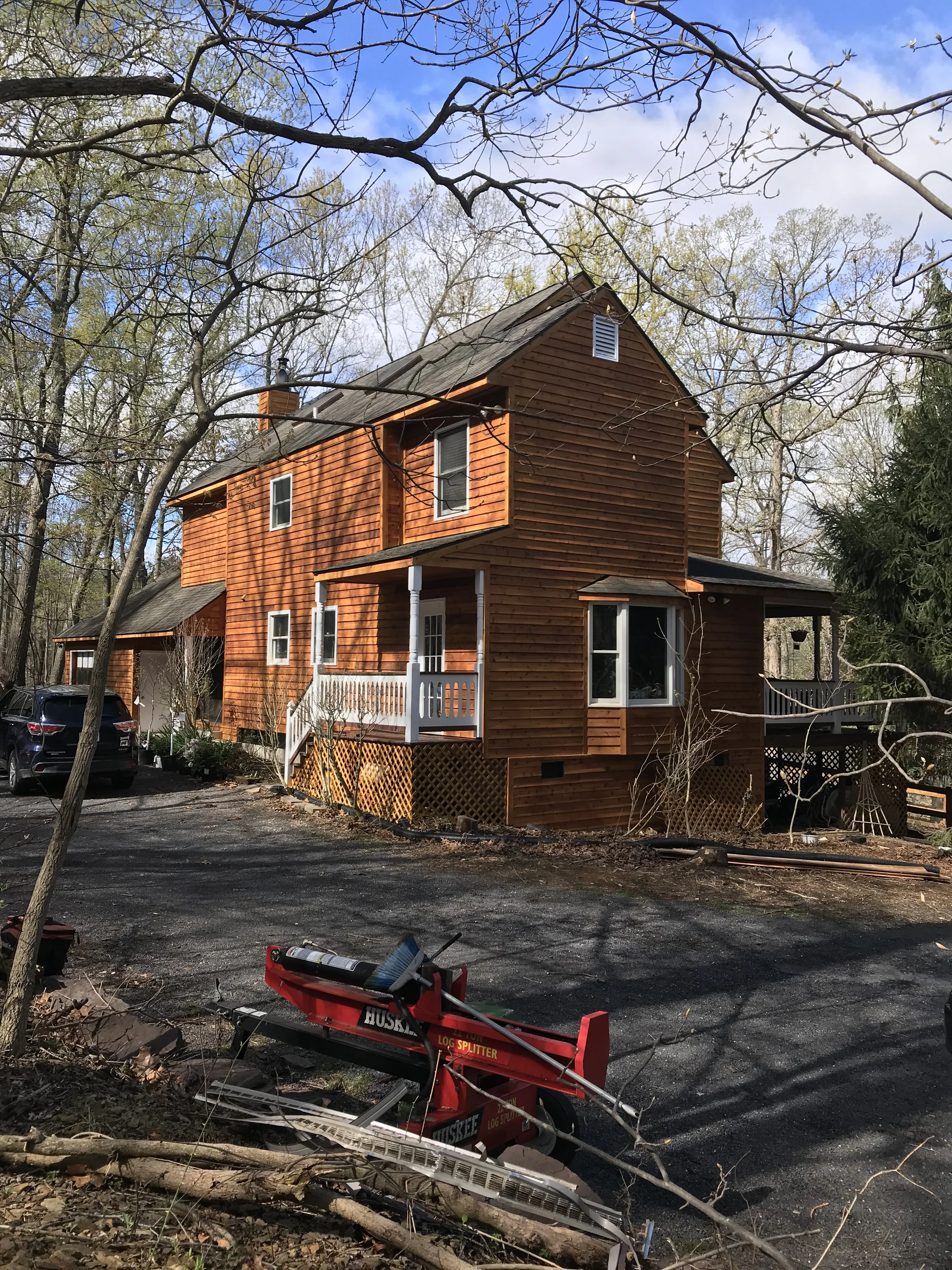 Two-story colonial home with orange-brown stained cedar siding, white trim, and gable roof