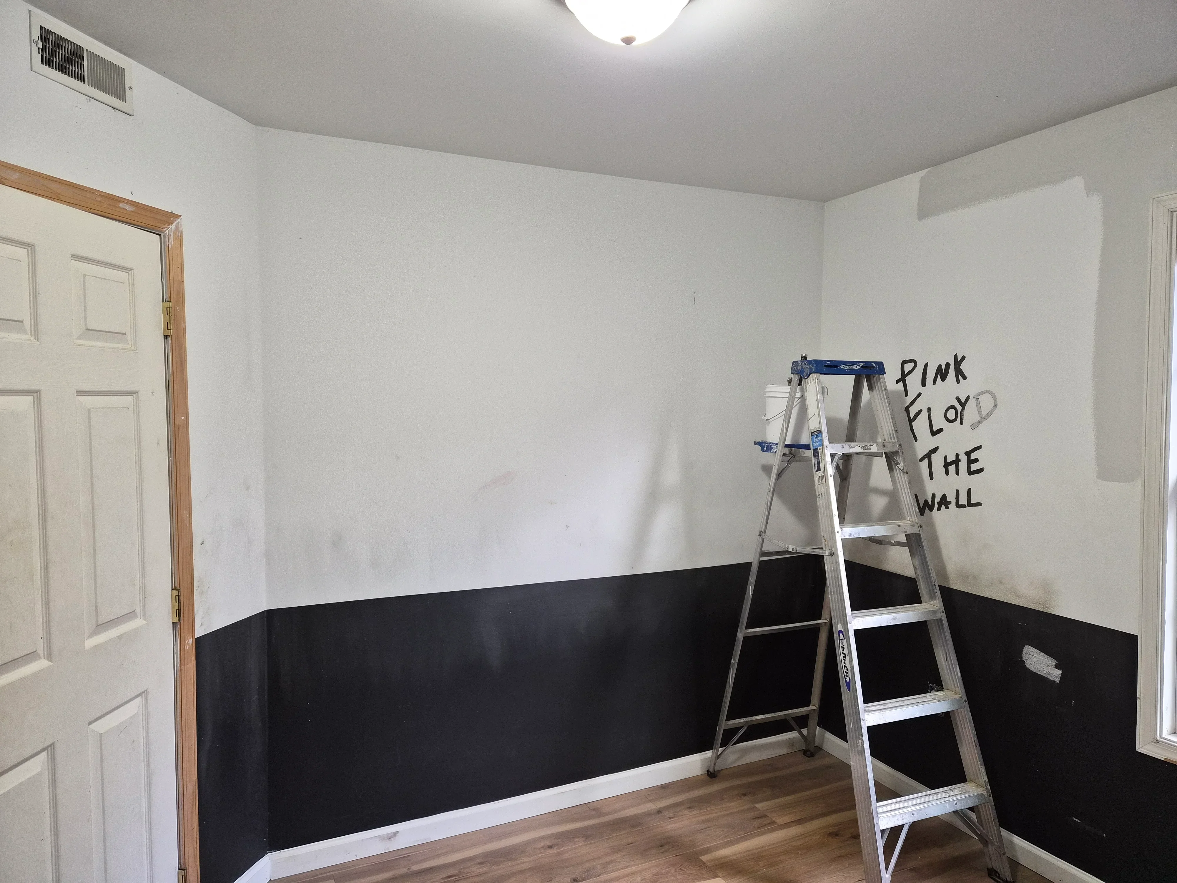 Two-tone painted bedroom walls with white upper half and black lower half, clean horizontal division line